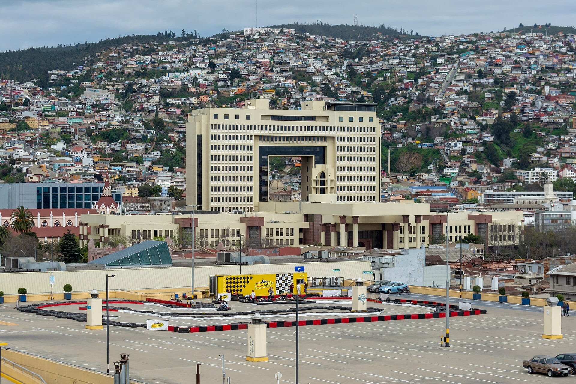 El edificio beige del Congreso Nacional de Chile frente a un cerro de casas de colores en Valparaíso.