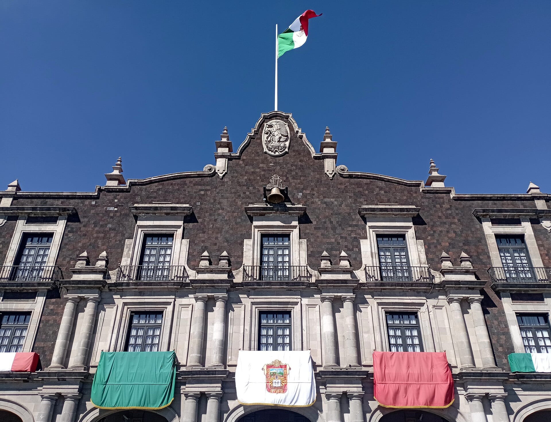 La fachada barroca del Palacio de Gobierno del Estado de México, en Toluca, con la bandera nacional ondeando en su remate.