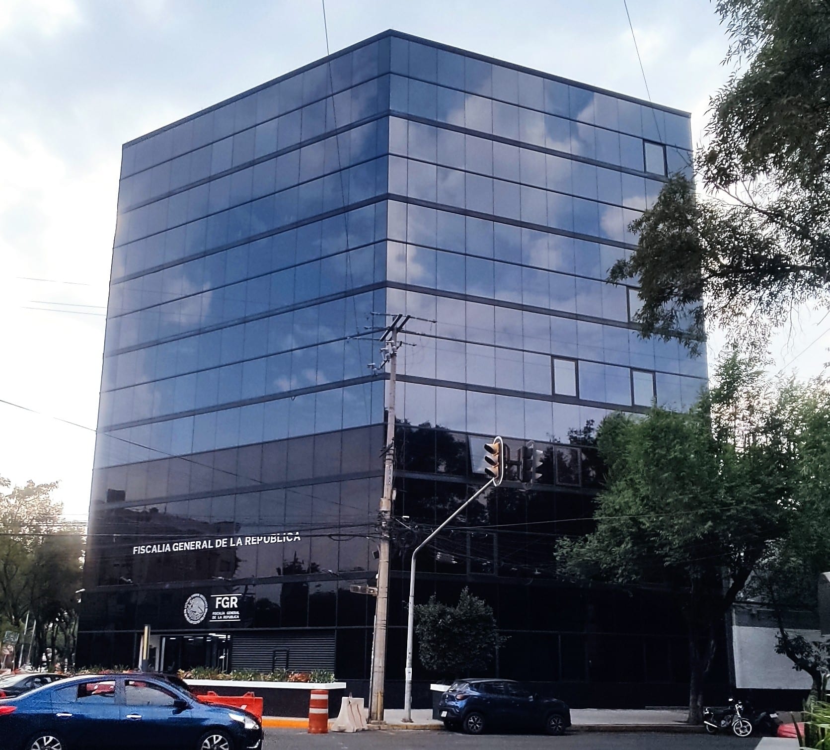 Fachada de cristal oscuro de un edificio de siete pisos con el rótulo Fiscalía General de la República y el logotipo de la FGR en la planta baja.