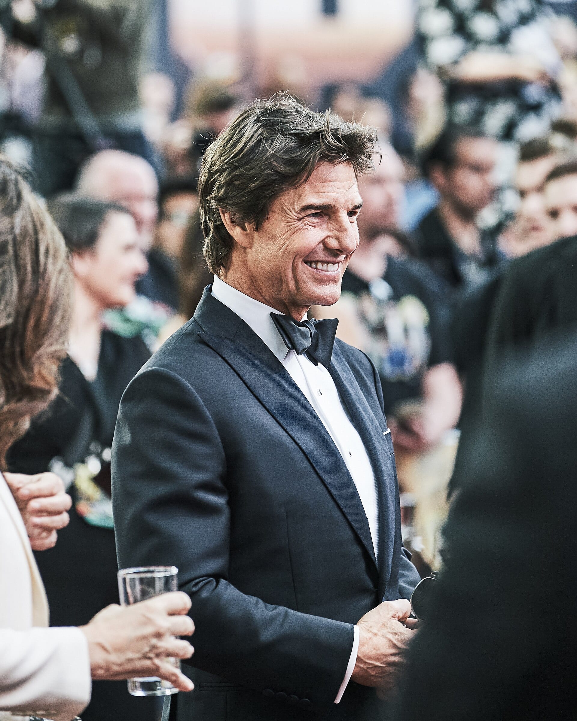 Tom Cruise de traje oscuro posa frente a la prensa en el estreno londinense de Top Gun: Maverick, en mayo de 2022.