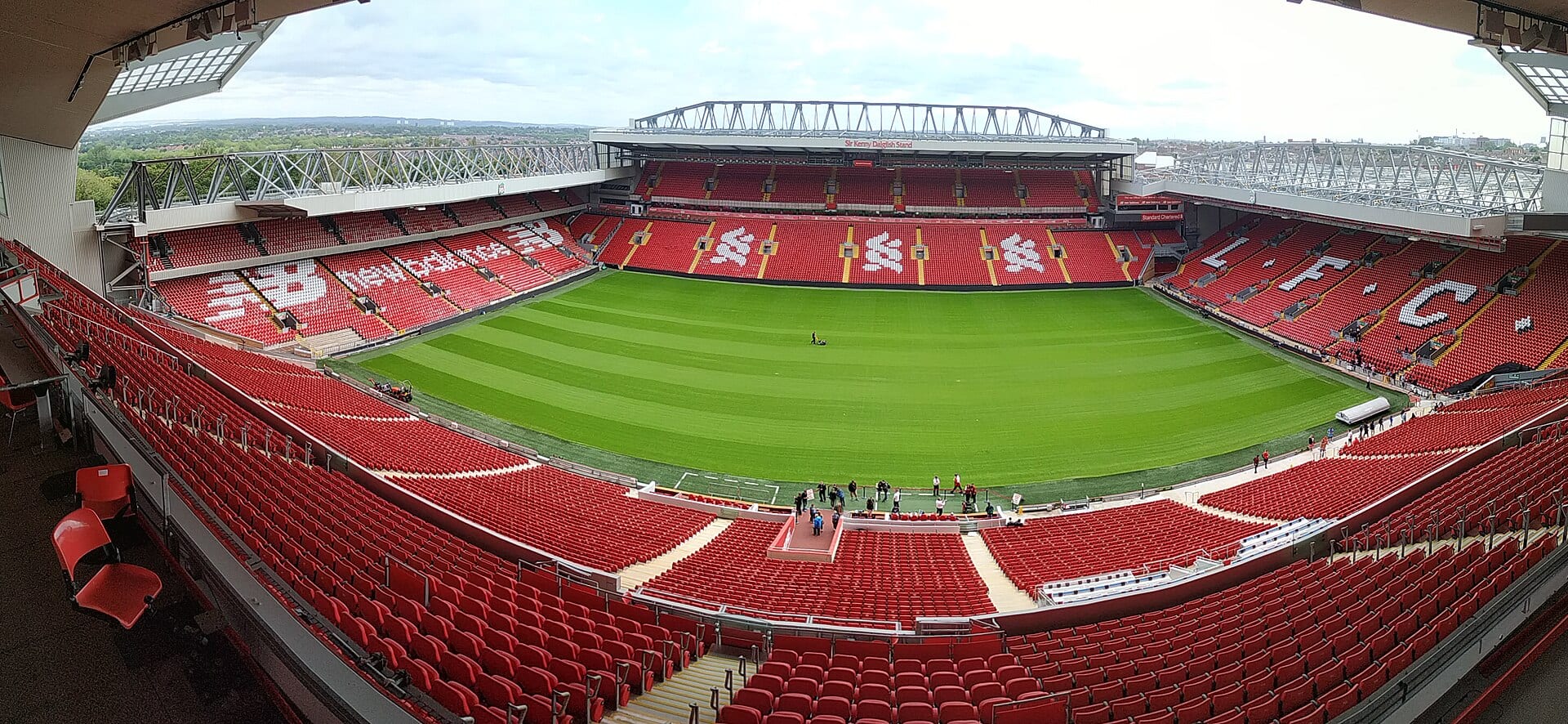 Panoramic view of Anfield's red stands from the main stand, with the pitch mown in stripes.