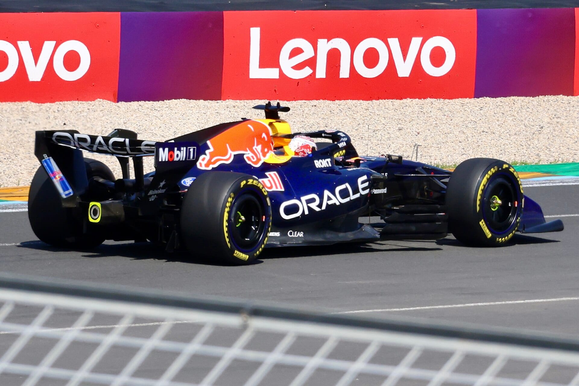 A navy blue Red Bull car on yellow-marked Pirelli tires takes a corner beside an advertising wall.
