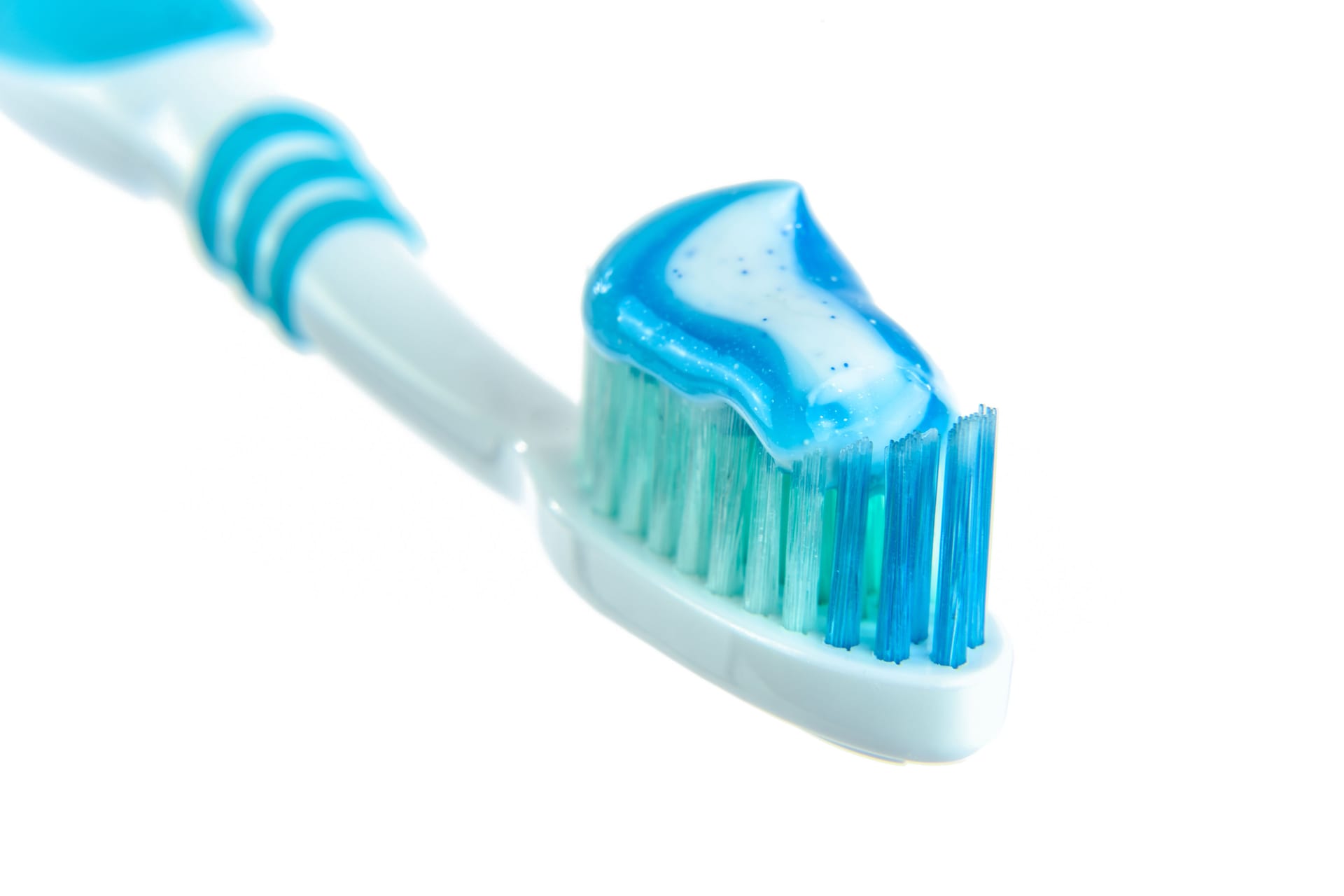 Un cepillo de dientes con pasta dental azul y blanca sobre las cerdas.