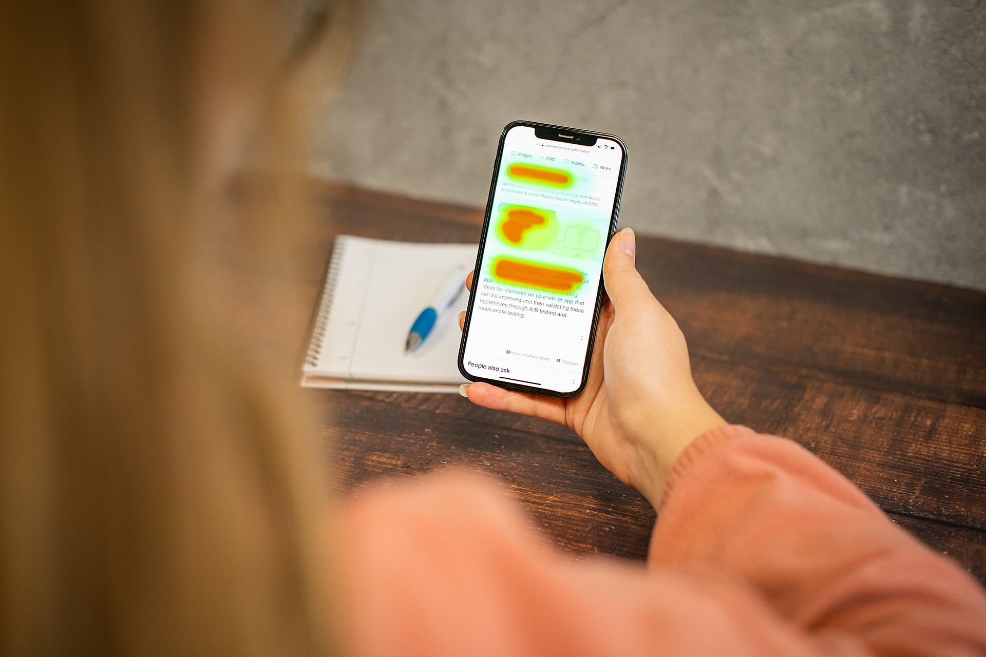 A person holds a phone whose browser shows colored blotches over the text of a web page.