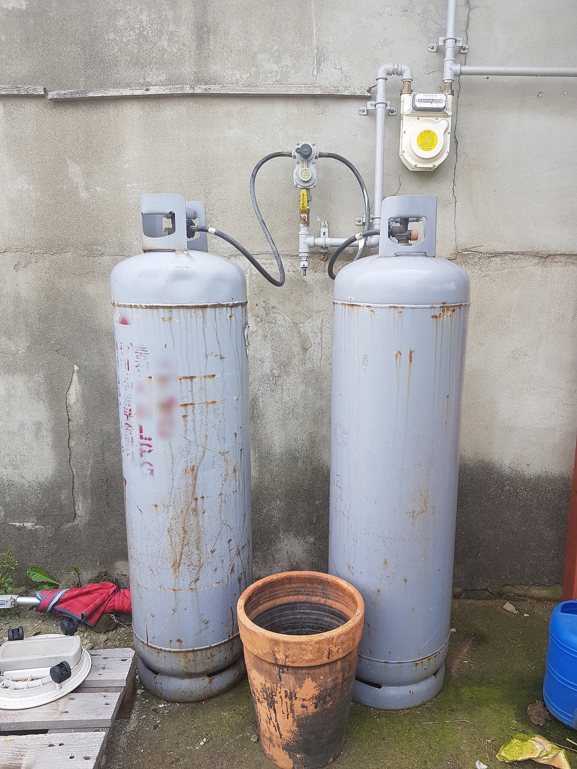 Dos tanques metálicos de gas LP conectados por mangueras a un medidor instalado en la pared de una vivienda.