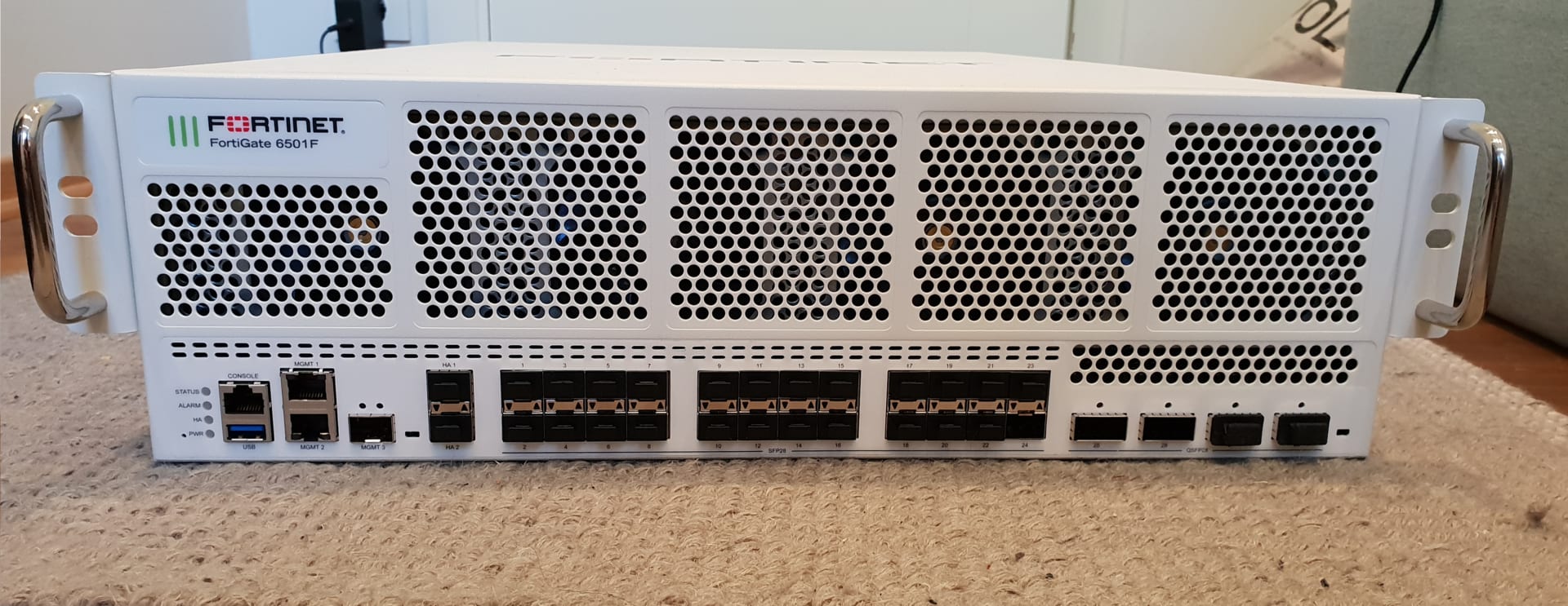 Front of a white rack-mounted appliance with the Fortinet logo and the words FortiGate 6501F, showing ventilation grilles and network ports.