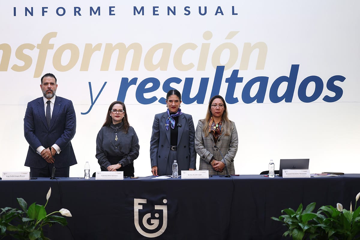 Cuatro funcionarios de pie tras una mesa con el logotipo de la Fiscalía, bajo el letrero del informe mensual.
