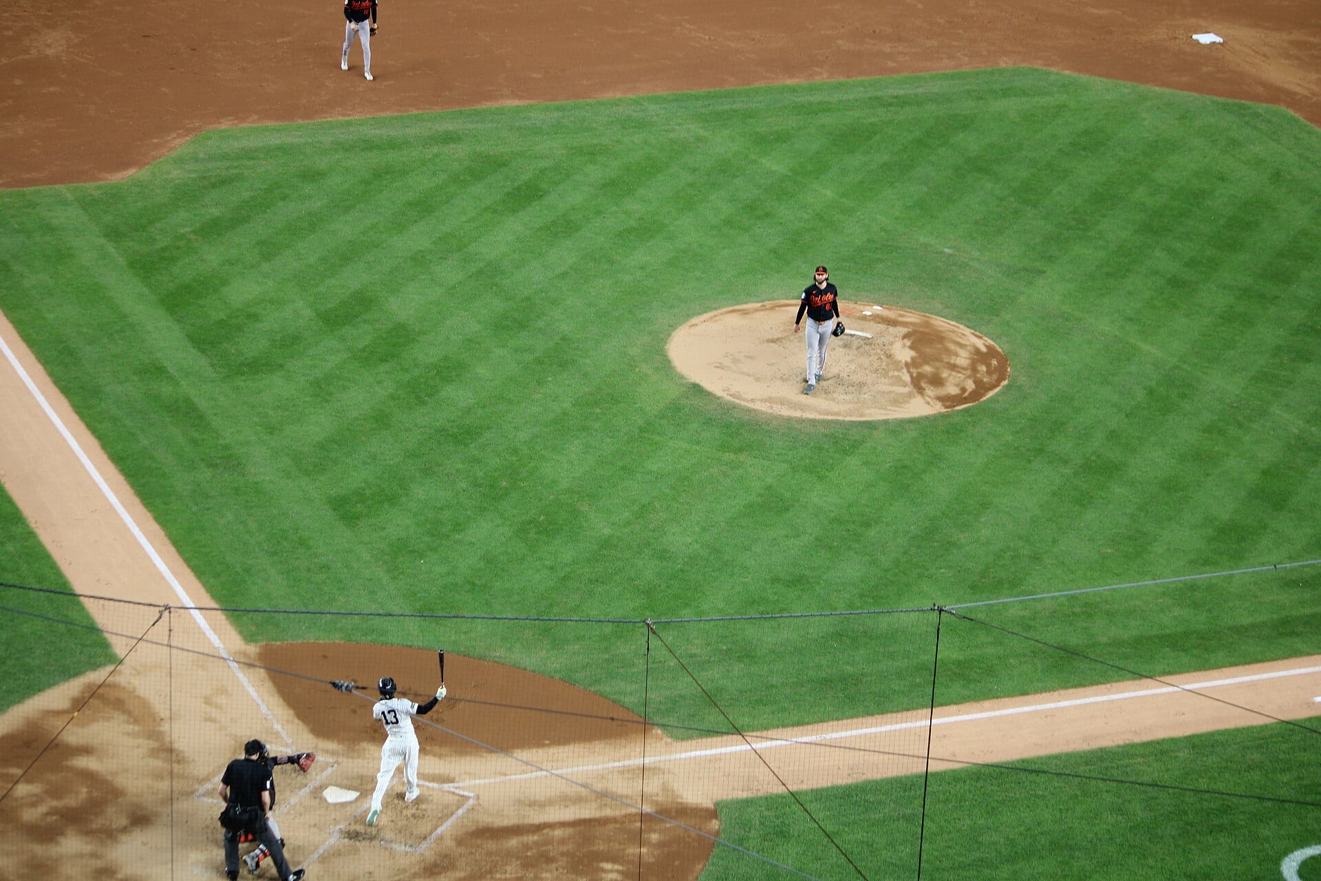 Un bateador de los Yankees con uniforme de rayas finas se prepara en el plato frente al lanzador de los Orioles, en una vista aérea del campo del Yankee Stadium.