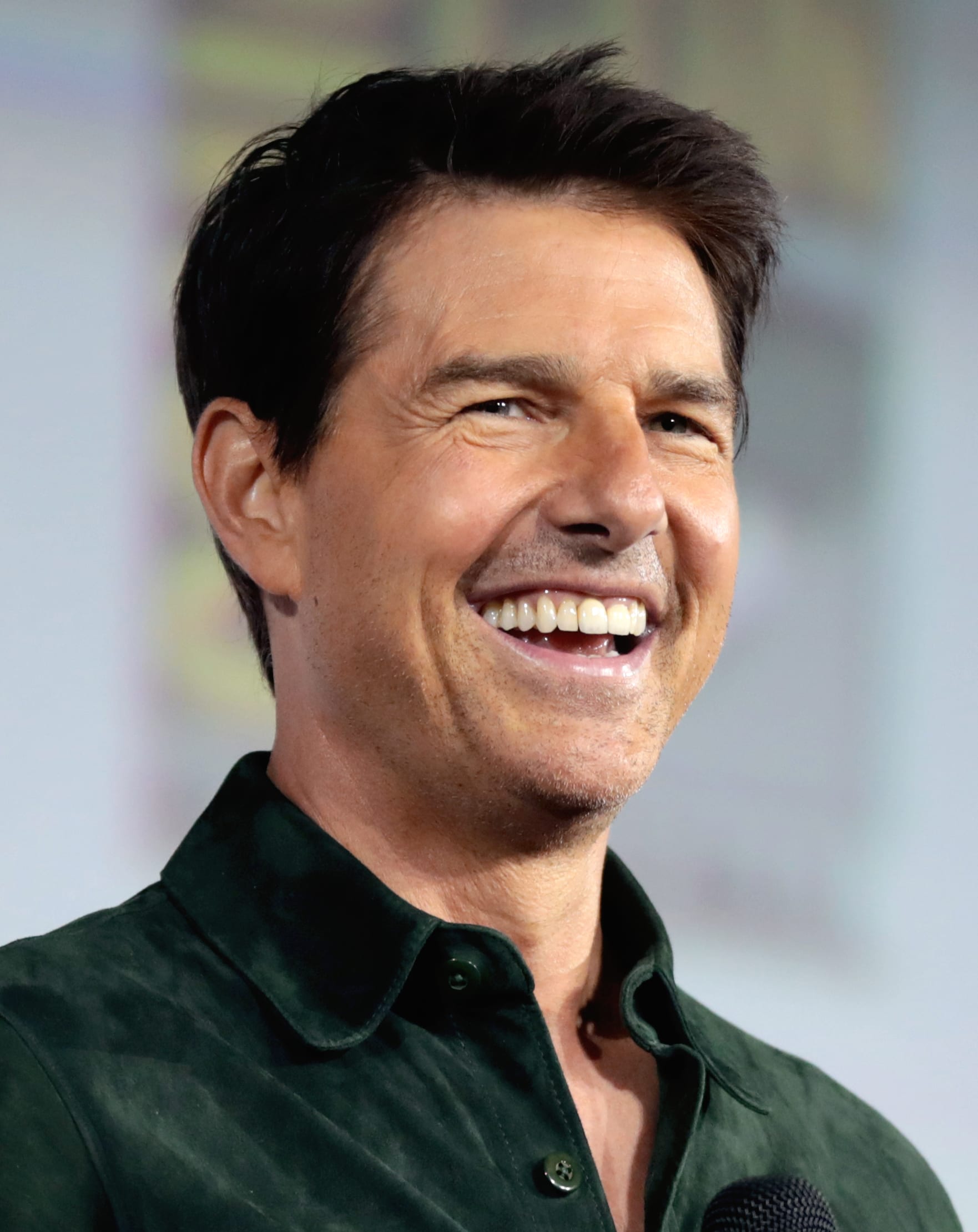 Tom Cruise sonríe con camisa verde oscura y un micrófono frente a él, durante un panel de la Comic-Con de San Diego de 2019.