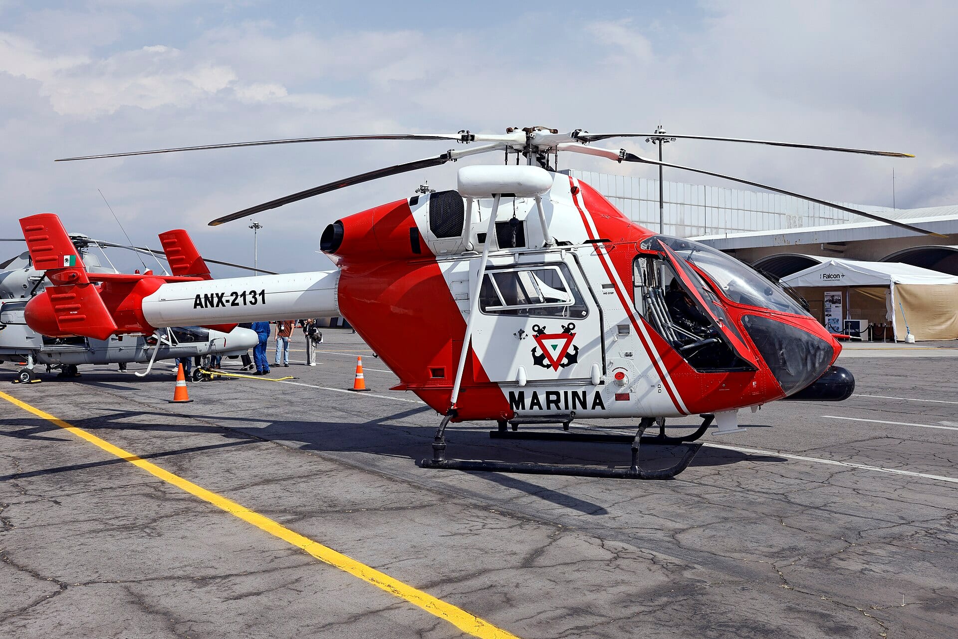 Un helicóptero MD 902 Explorer rojo y blanco con la palabra Marina en el costado, estacionado en una pista de concreto.