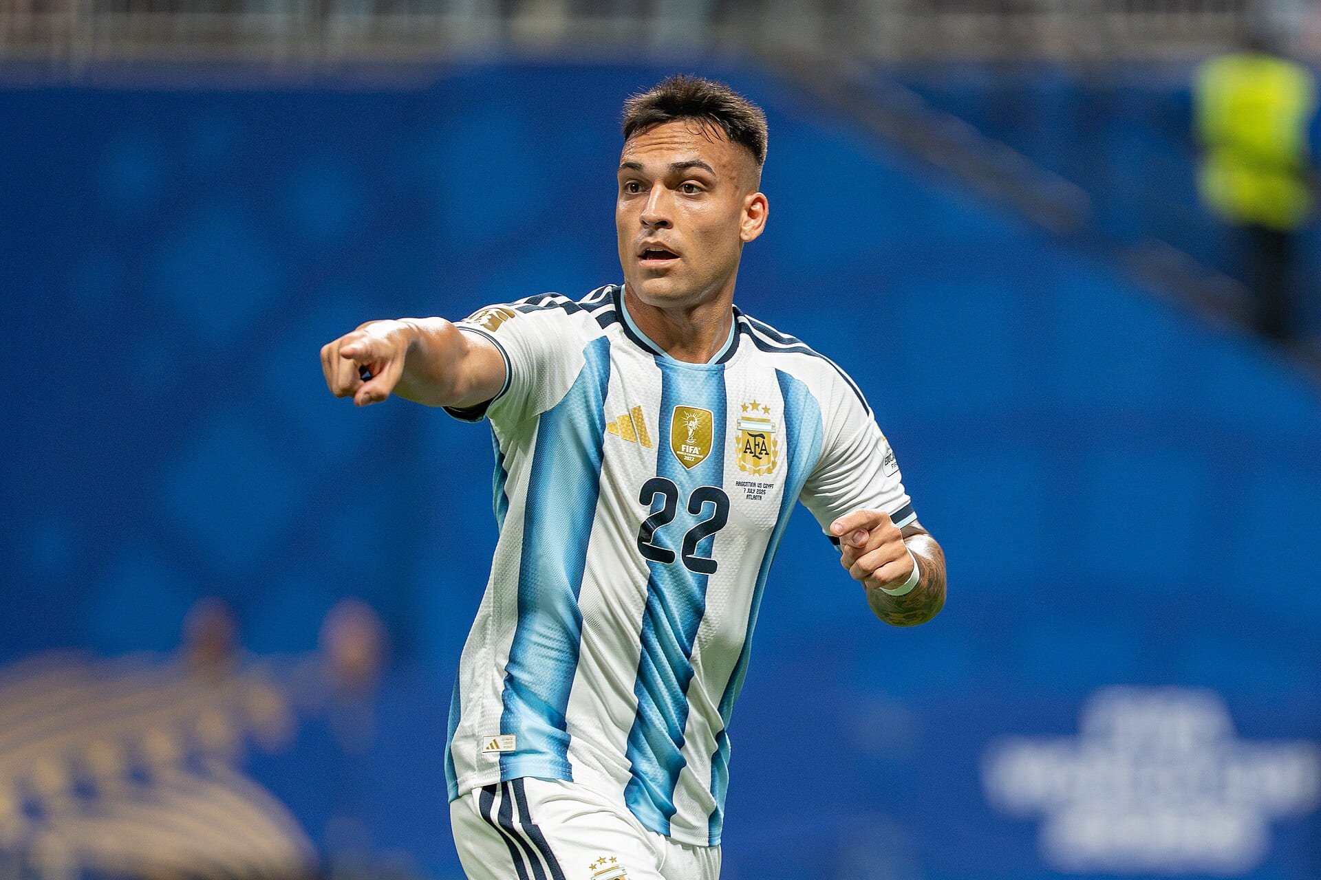 Lautaro Martínez, con la camiseta albiceleste número 22 de Argentina, señala con el brazo derecho durante un partido en un estadio.