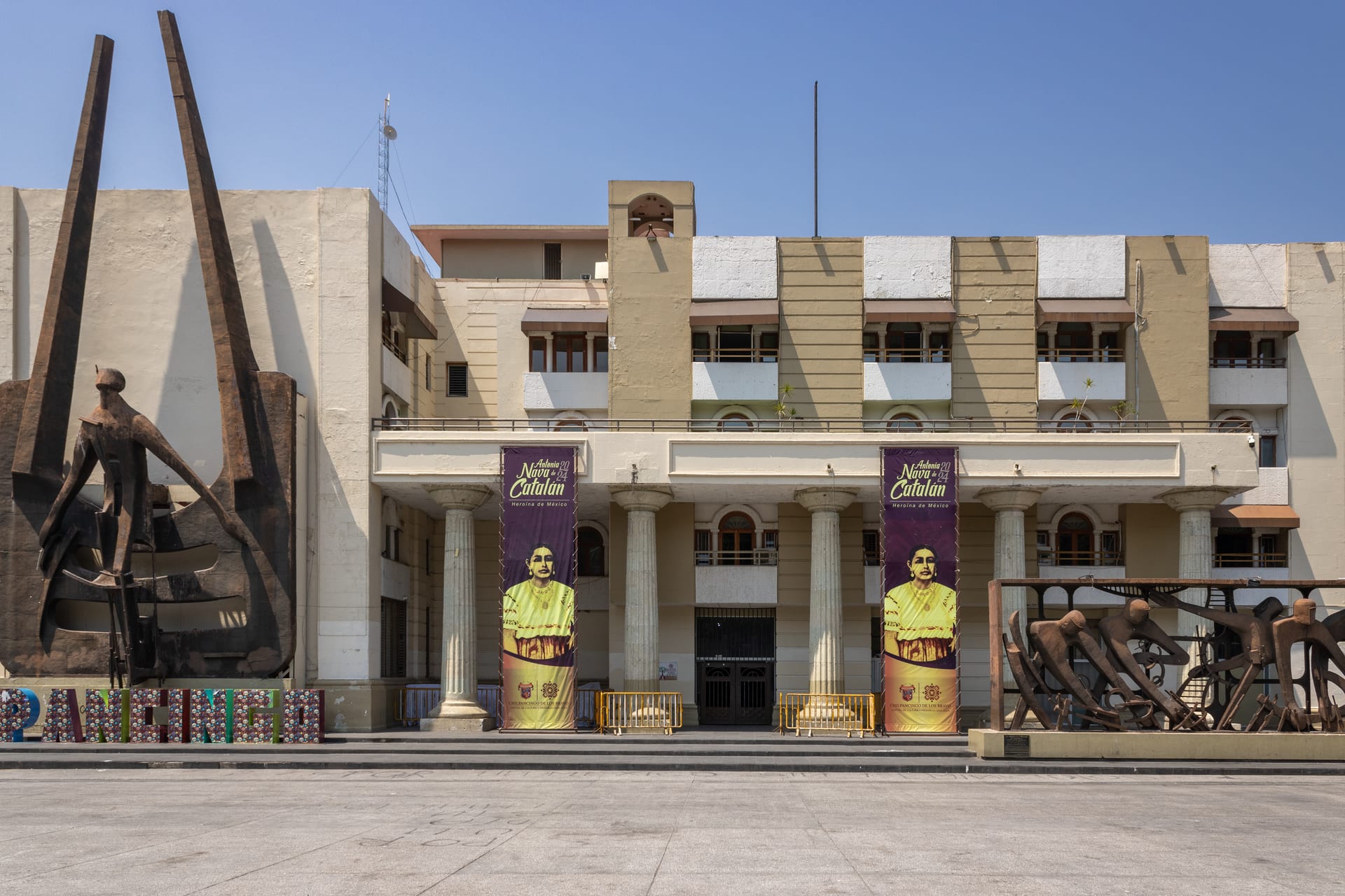 Fachada del Ayuntamiento de Chilpancingo con columnas y dos mantas verticales, vista desde la plaza cívica.