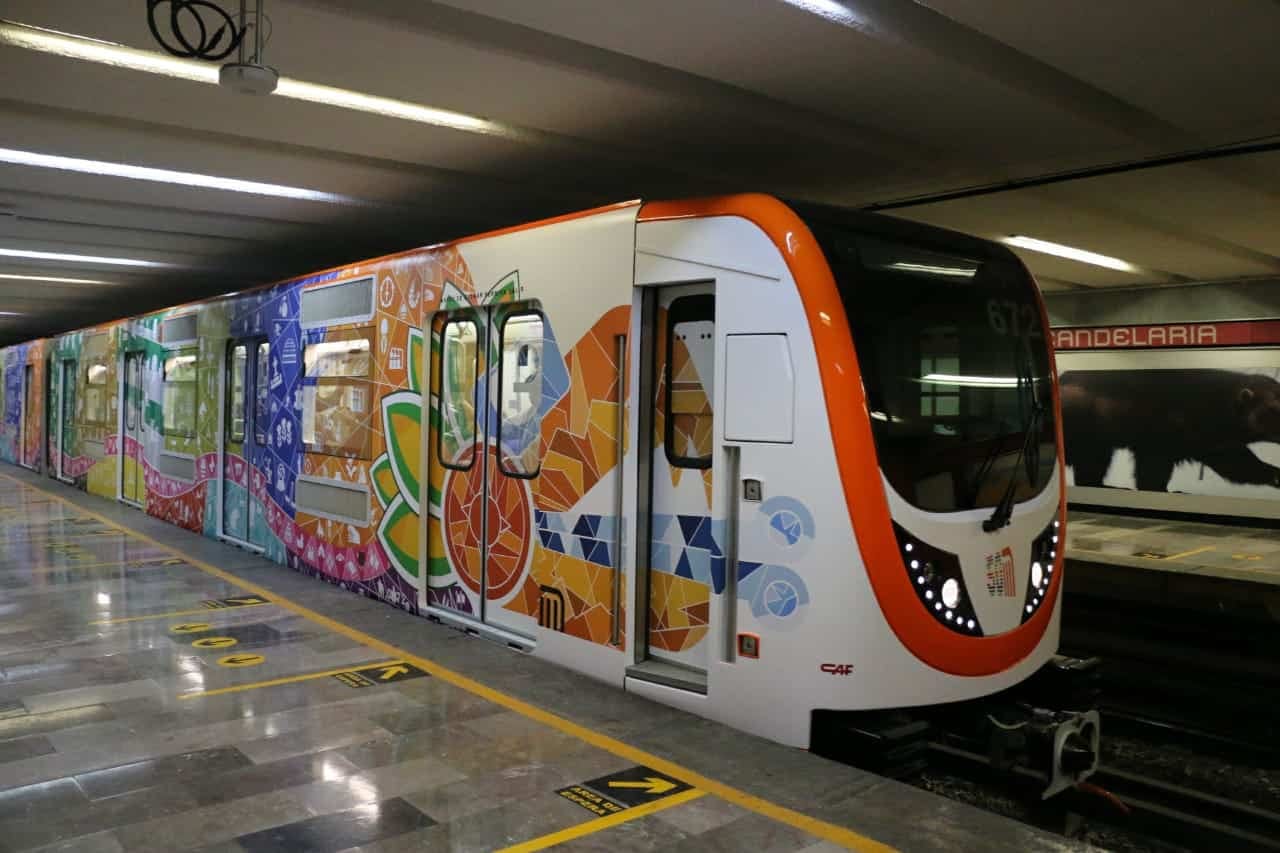Un tren del Metro de la Ciudad de México, con vagones decorados de colores, detenido en el andén de la estación Candelaria.