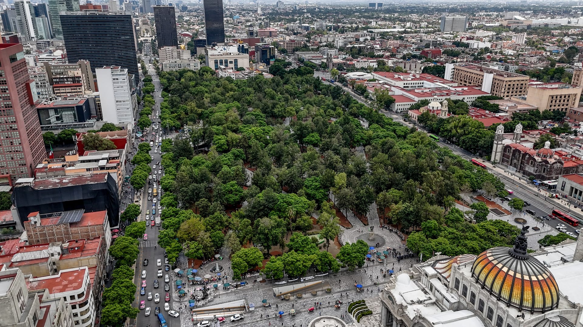 Vista aérea de la Alameda Central de la Ciudad de México, con sus árboles, caminos y fuentes rodeados de edificios del centro.