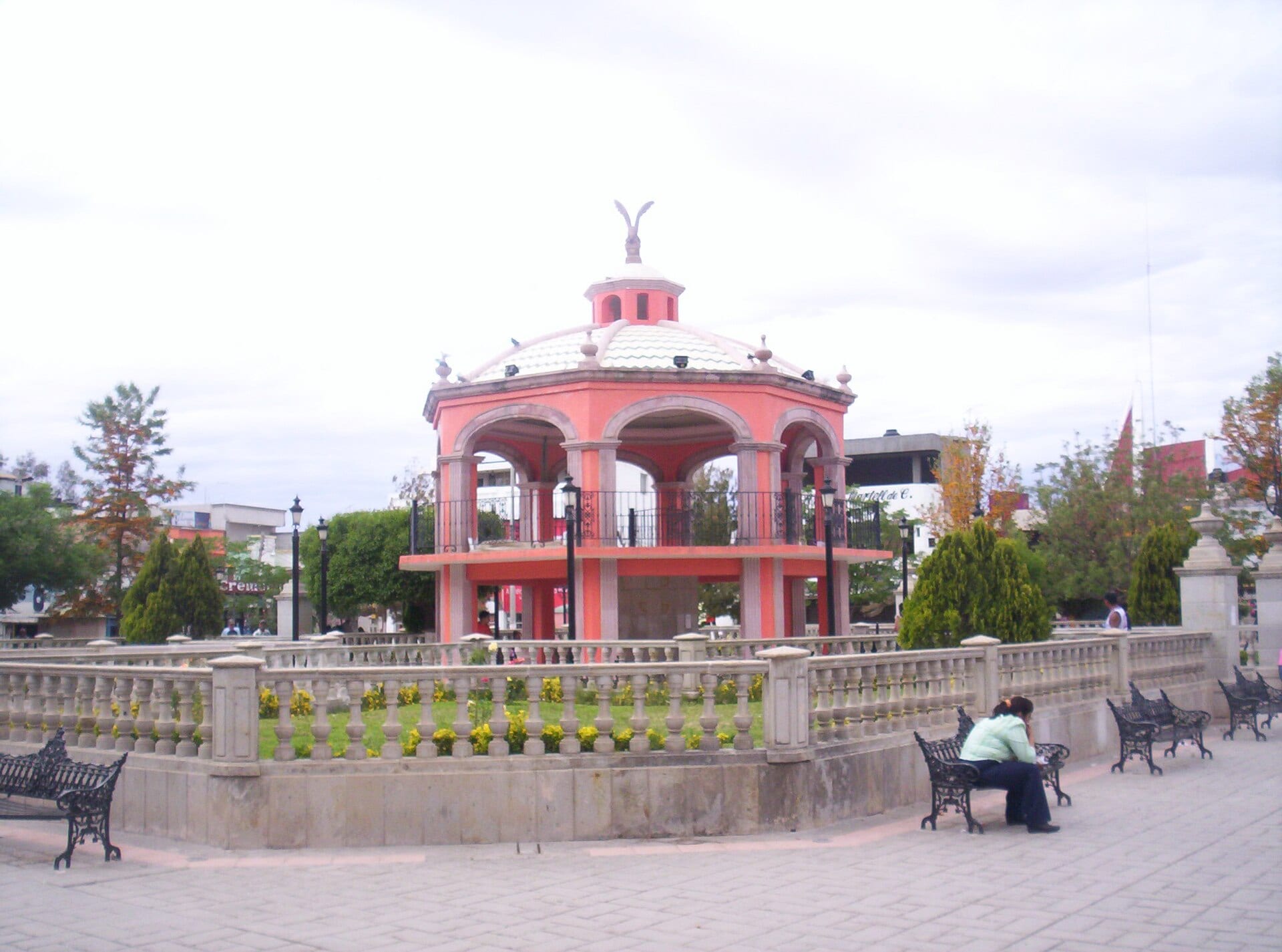 Quiosco rosado de la plaza principal de Río Grande, Zacatecas, con bancas y árboles alrededor.