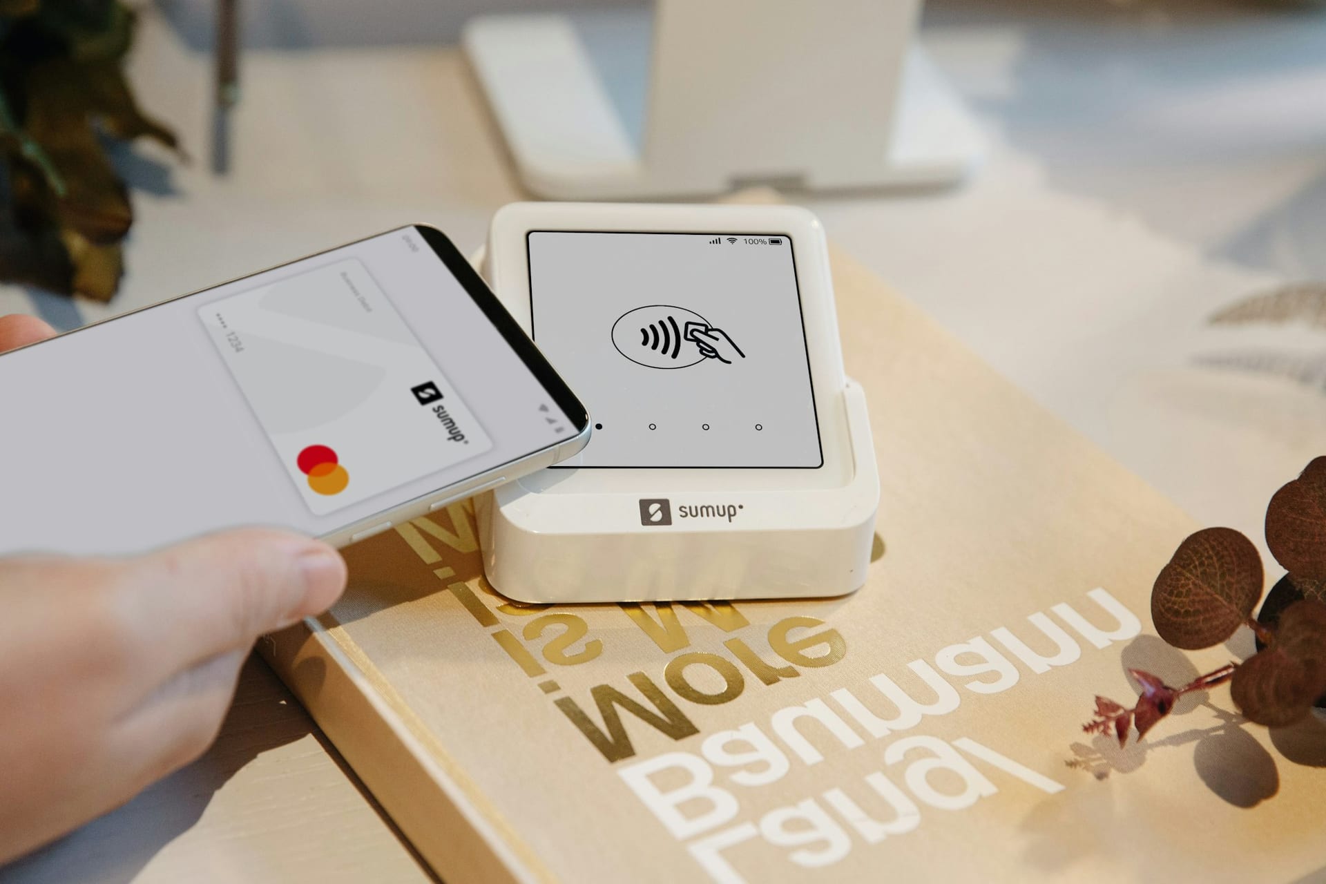 Un teléfono móvil se acerca a un lector de tarjetas blanco que muestra el símbolo de pago sin contacto.