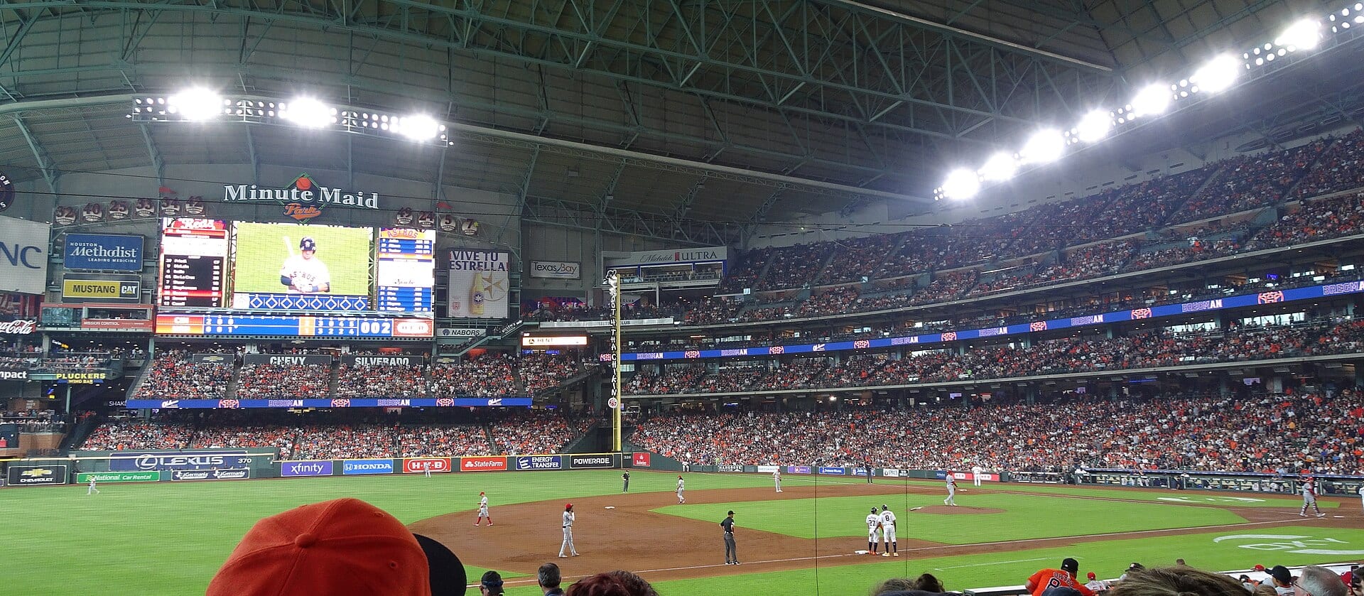 Terreno de juego y gradas llenas de un estadio de béisbol techado durante un partido en tarde despejada.