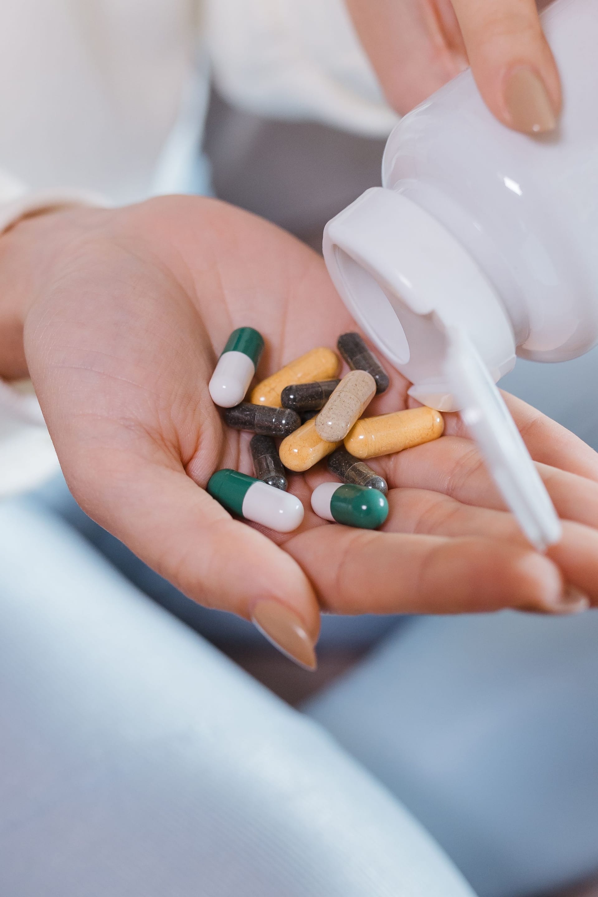 Una mano sostiene varias pastillas de distintos colores y tamaños sobre la palma abierta.