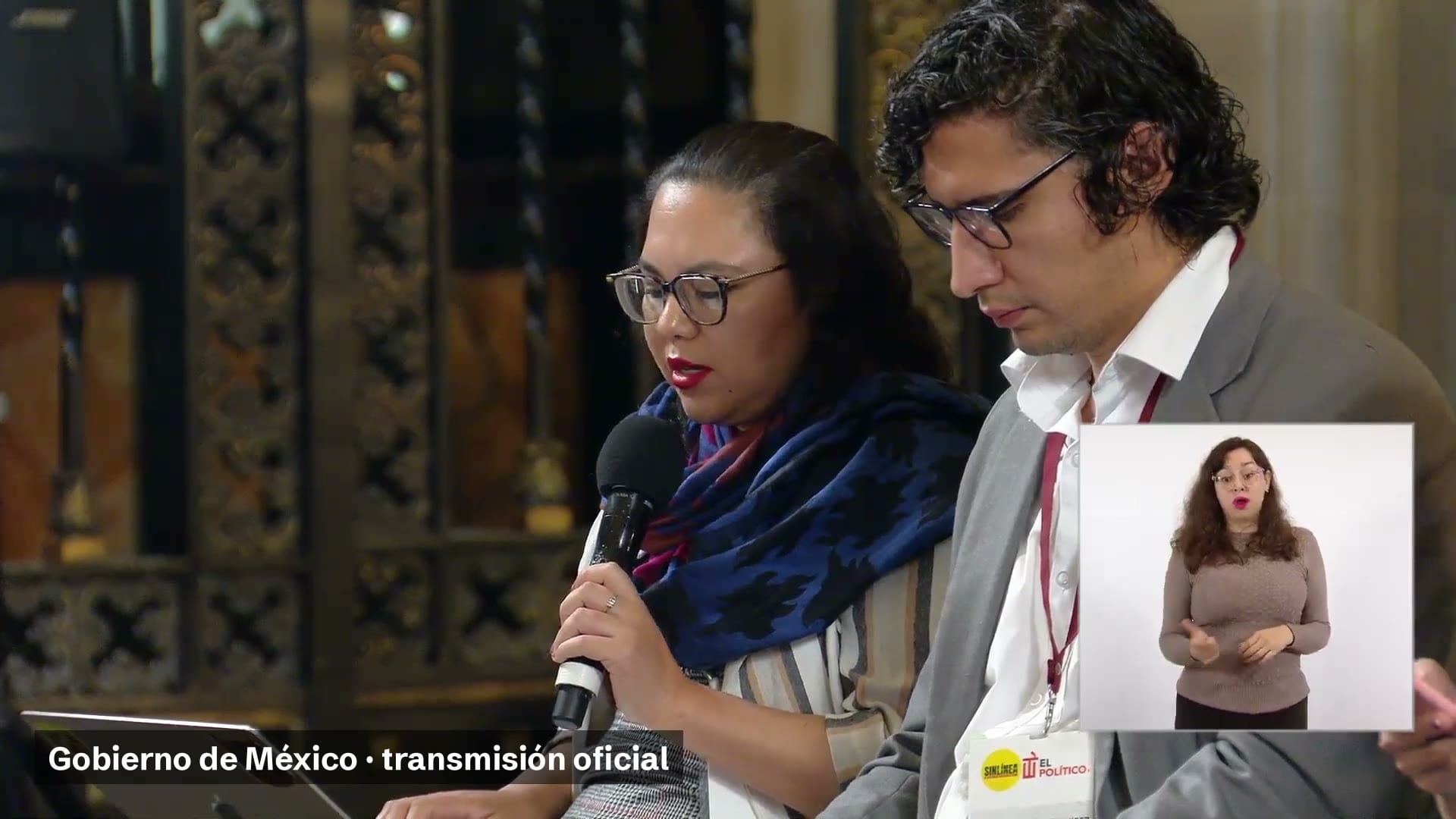 Una reportera con micrófono y un reportero a su lado durante la conferencia matutina, con intérprete de lengua de señas en un recuadro.