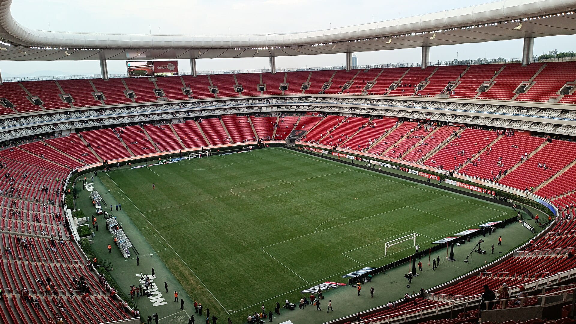 Interior del Estadio Akron visto desde lo alto de la cabecera, con la cancha de pasto y las gradas de asientos rojos casi vacías.