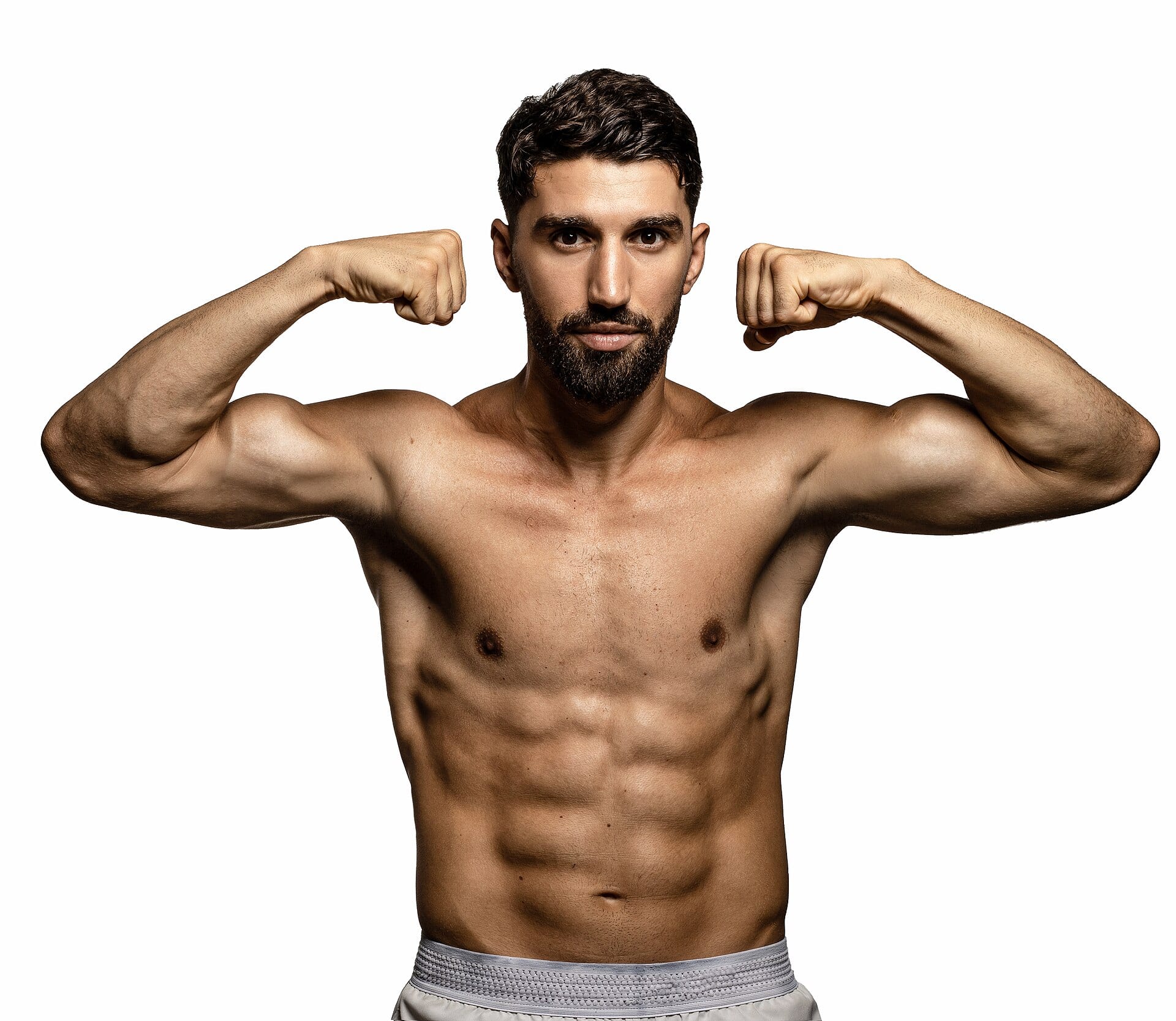 Ermal Hadribeaj posa sin camisa ante un fondo blanco, con los dos puños flexionados a la altura de la cabeza.
