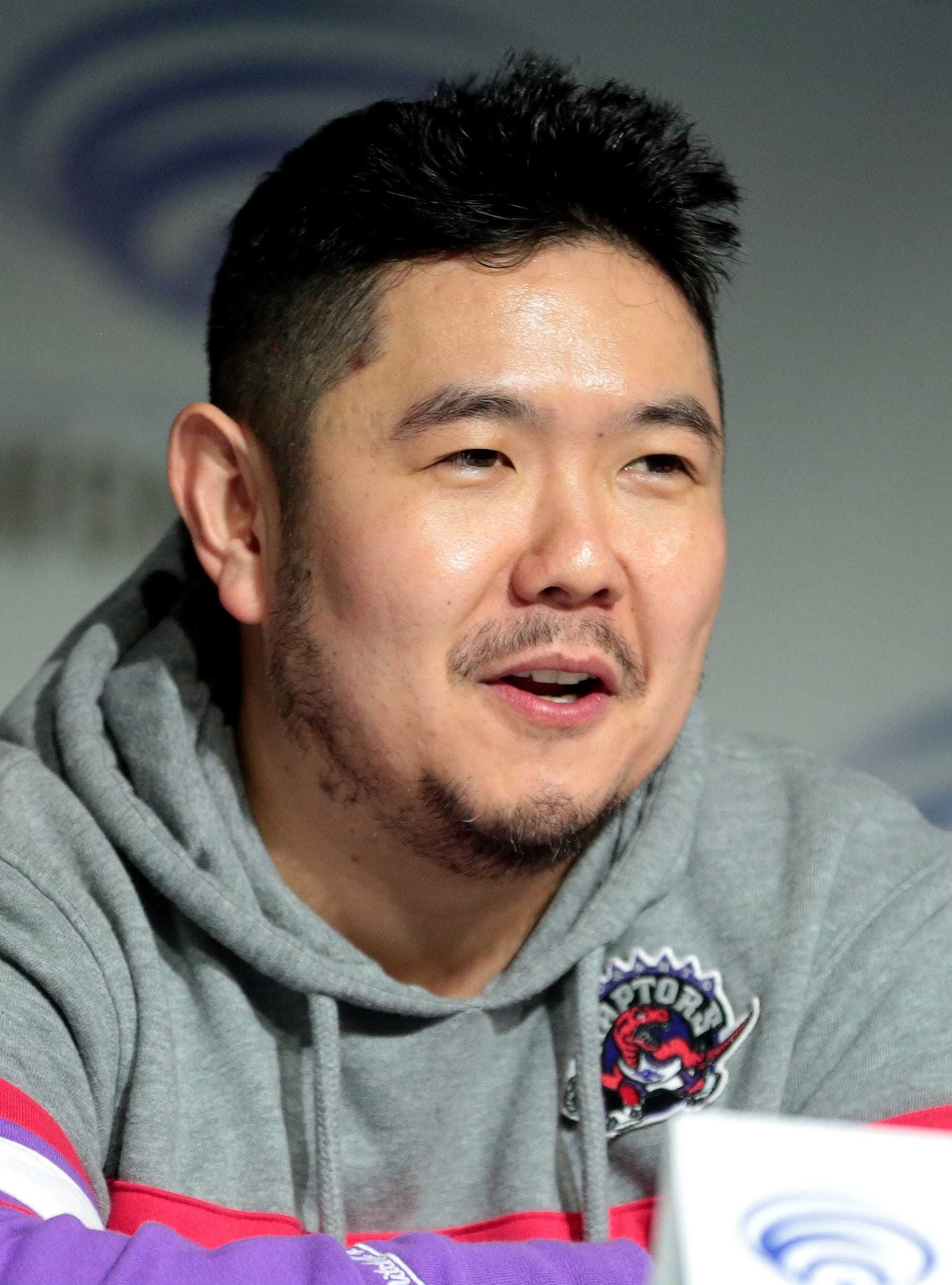 Eric Bauza, de pie, sonríe durante un panel en la convención WonderCon de 2018.