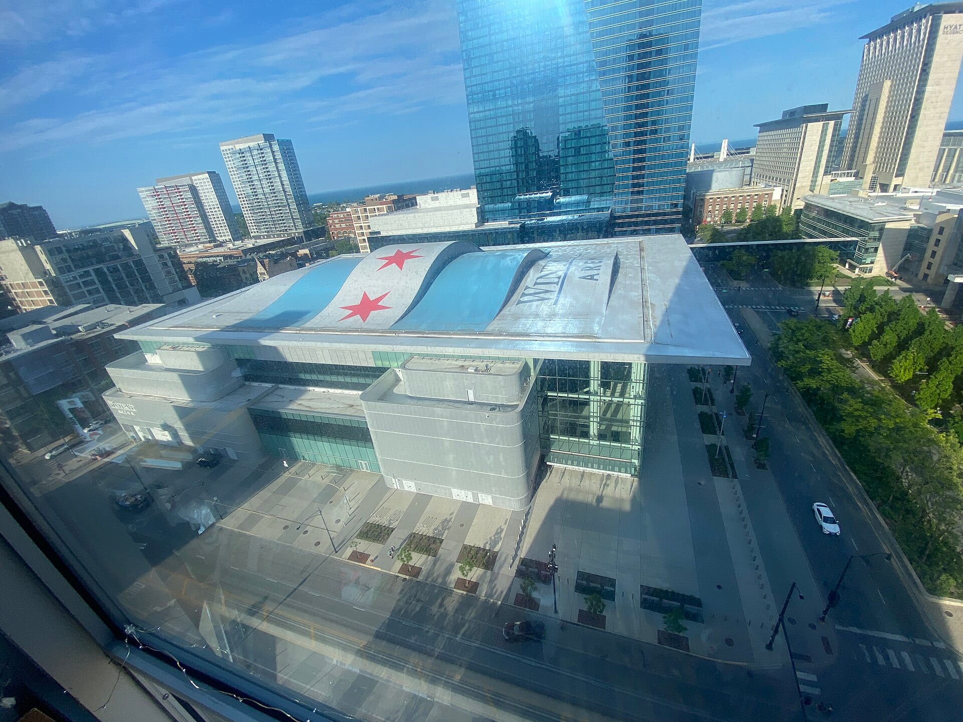 Vista aérea del Wintrust Arena de Chicago, con el techo pintado con la bandera de la ciudad y torres de vidrio alrededor.