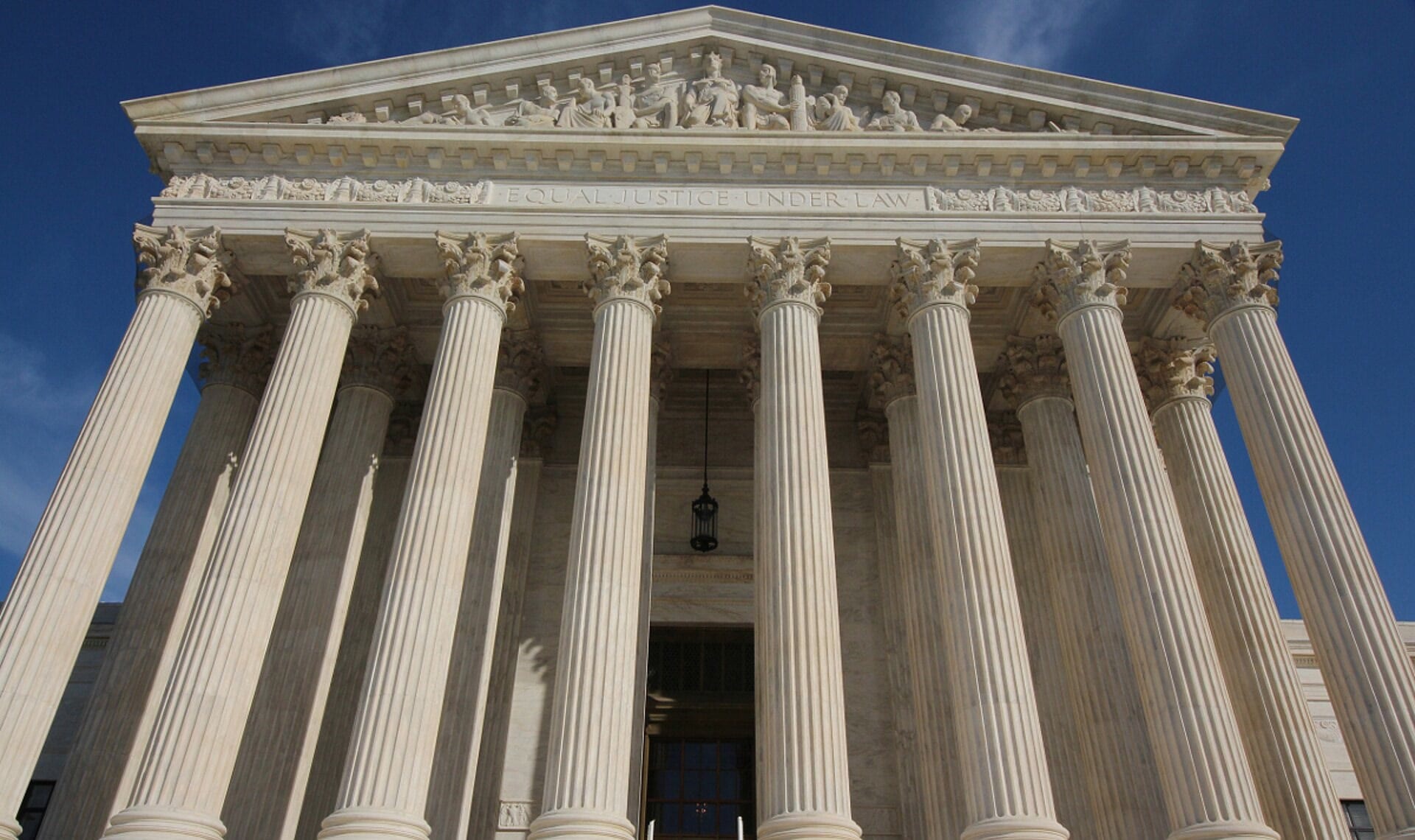 The marble front of the U.S. Supreme Court building seen from below, with its columns and the words Equal Justice Under Law carved above them.