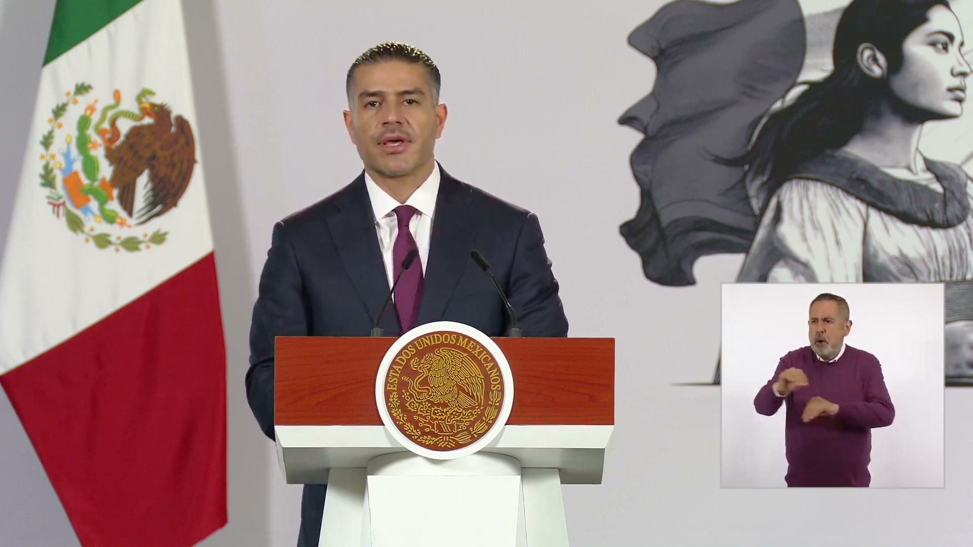 El secretario de Seguridad, Omar García Harfuch, habla en el podio de la conferencia matutina, junto a la bandera de México.
