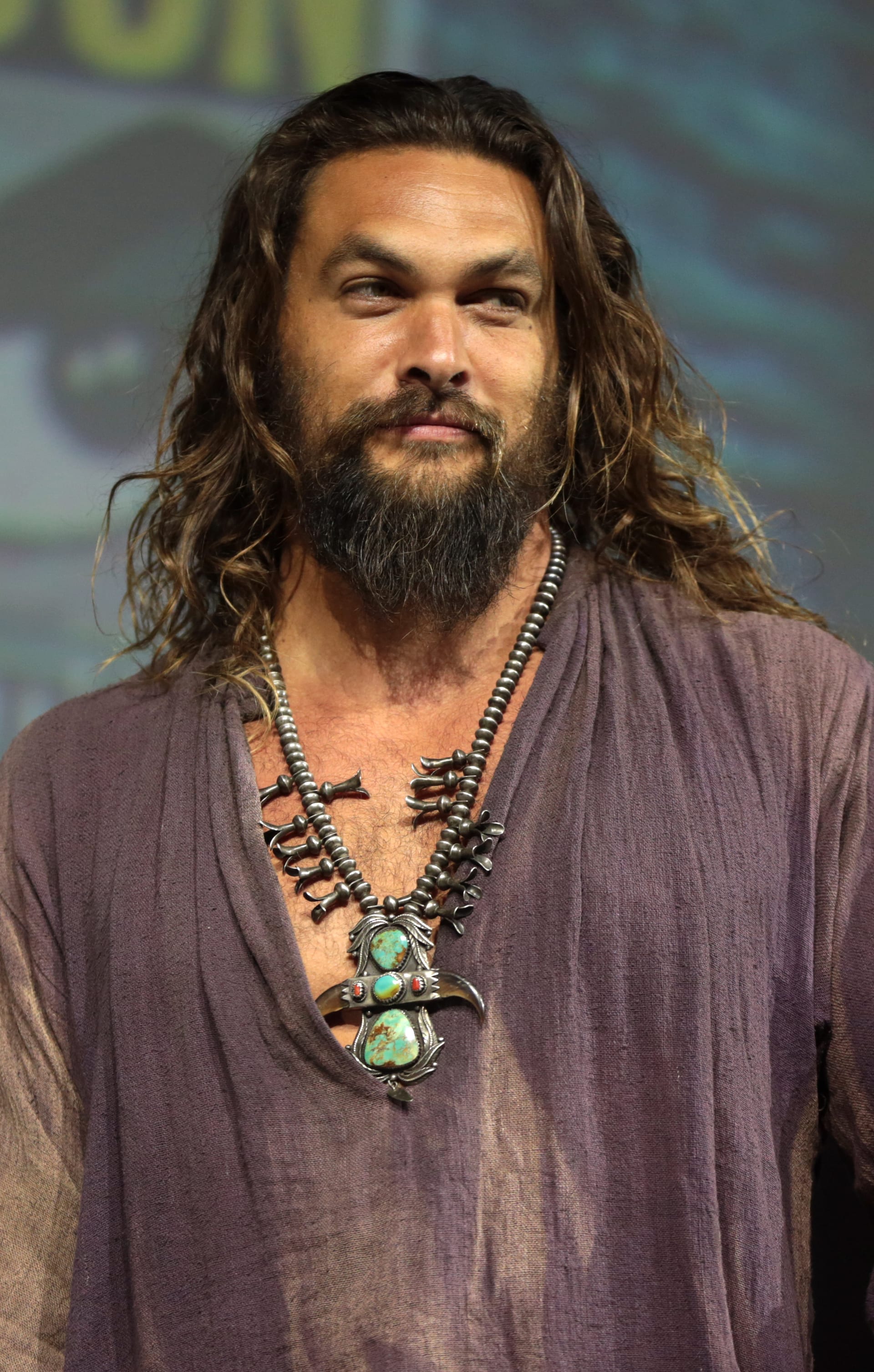 Retrato de Jason Momoa, de barba y cabello largo, durante un panel en una convención.