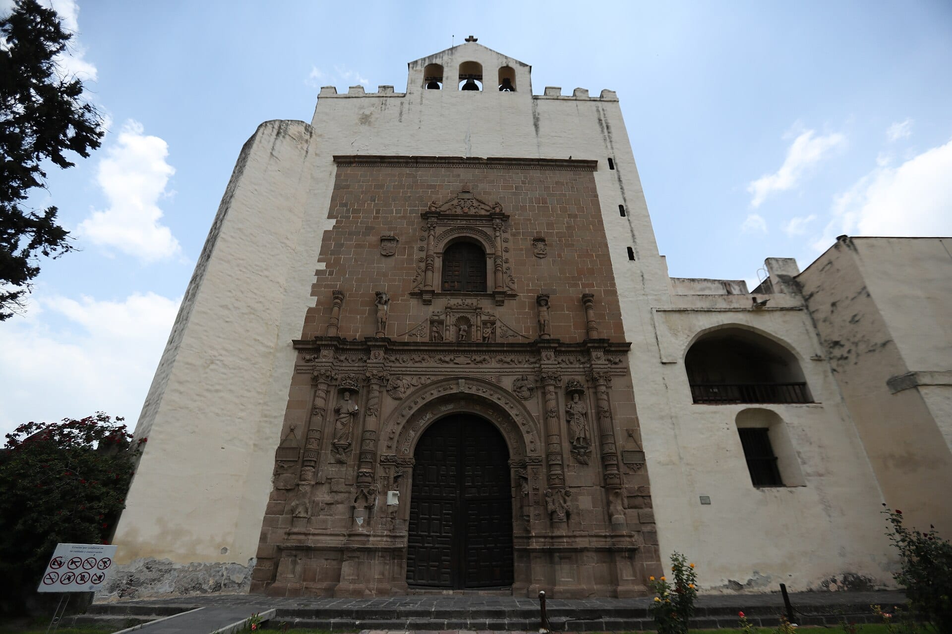 Fachada blanca y de cantera del exconvento de San Agustín, en Acolman, con su campanario y la portada tallada.