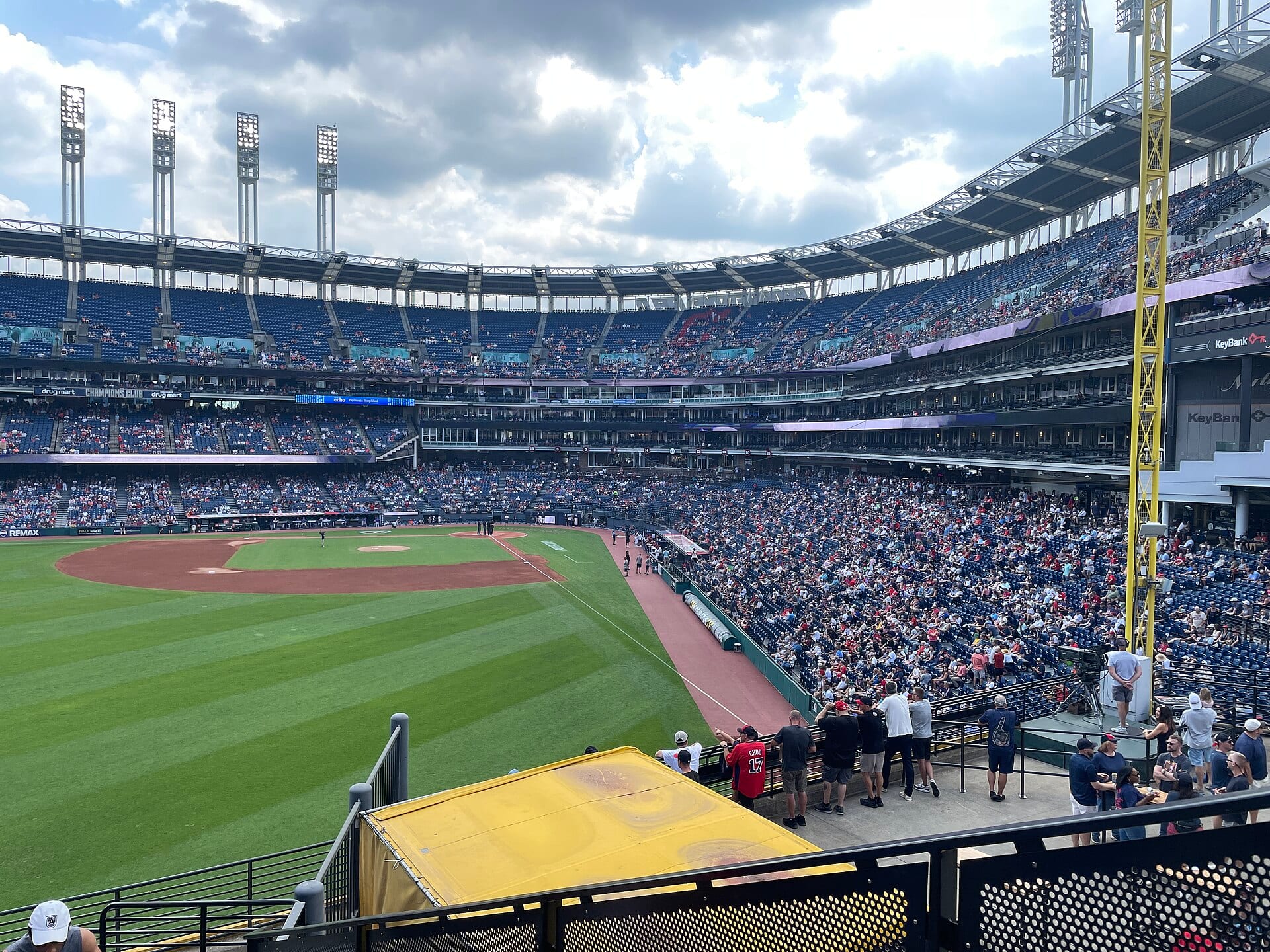 A daytime view of the field and stands at Progressive Field in Cleveland, with the infield on the left and light towers in the background.