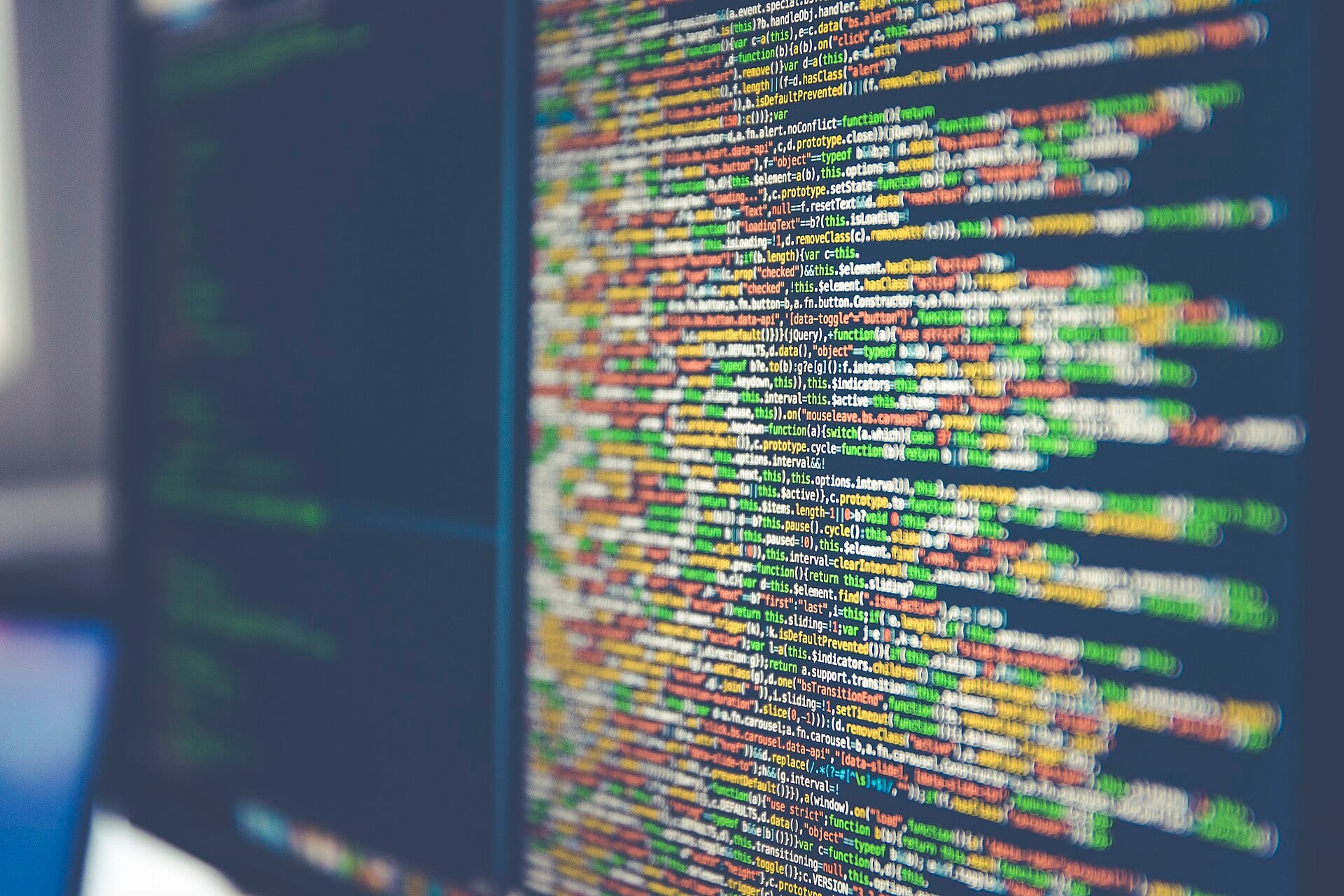 Computer screen showing lines of colorful code, blurred toward the edges.