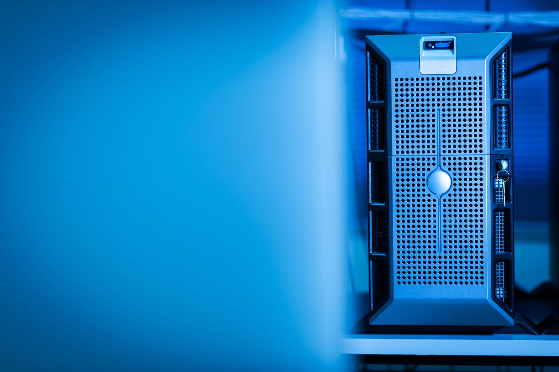 Un servidor de cómputo con múltiples cables conectados, iluminado en tonos azules dentro de un centro de datos.