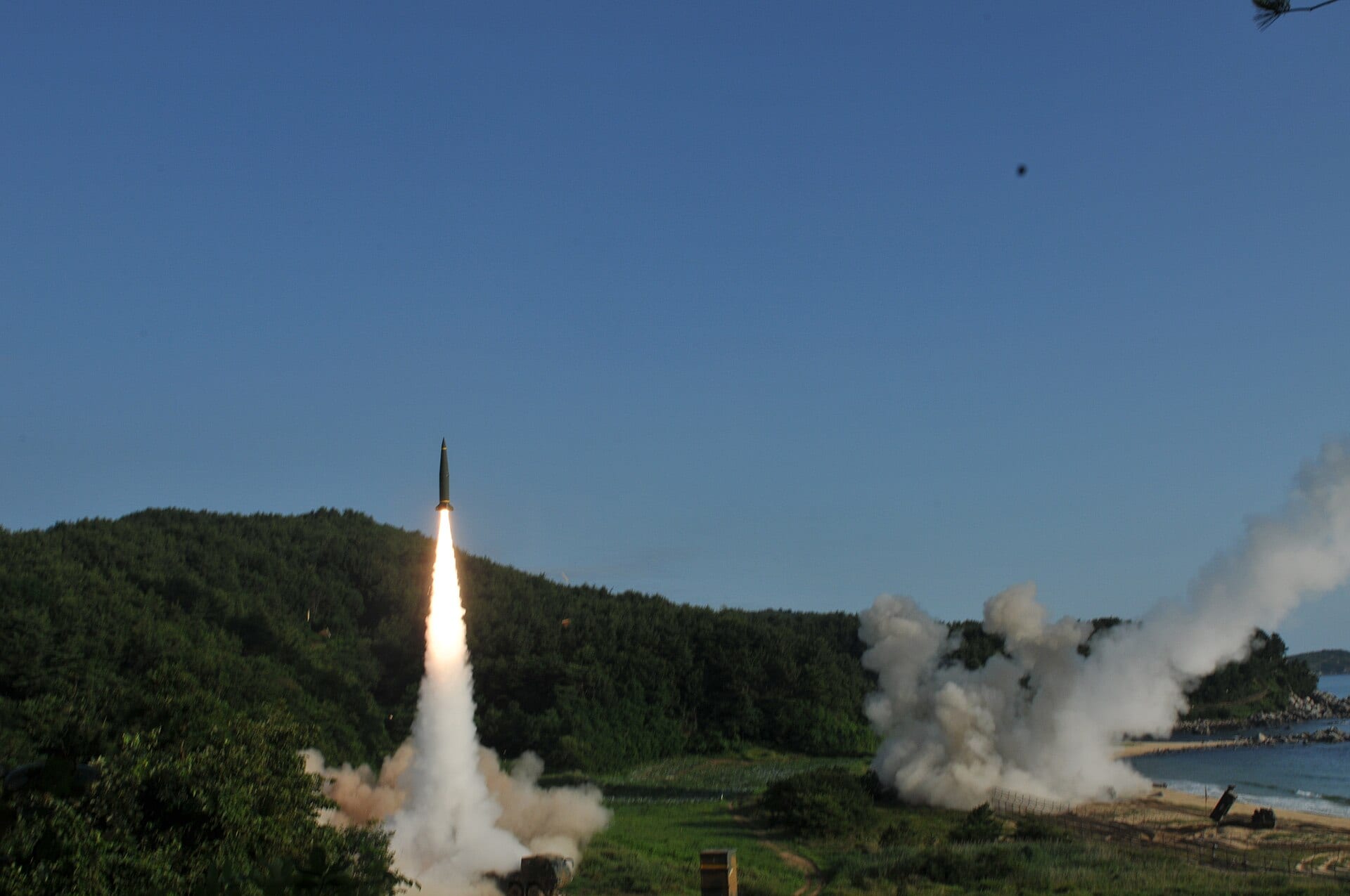 Un misil asciende con una larga columna de fuego y humo sobre una colina boscosa junto al mar, en un ejercicio militar de 2017 en Corea del Sur.