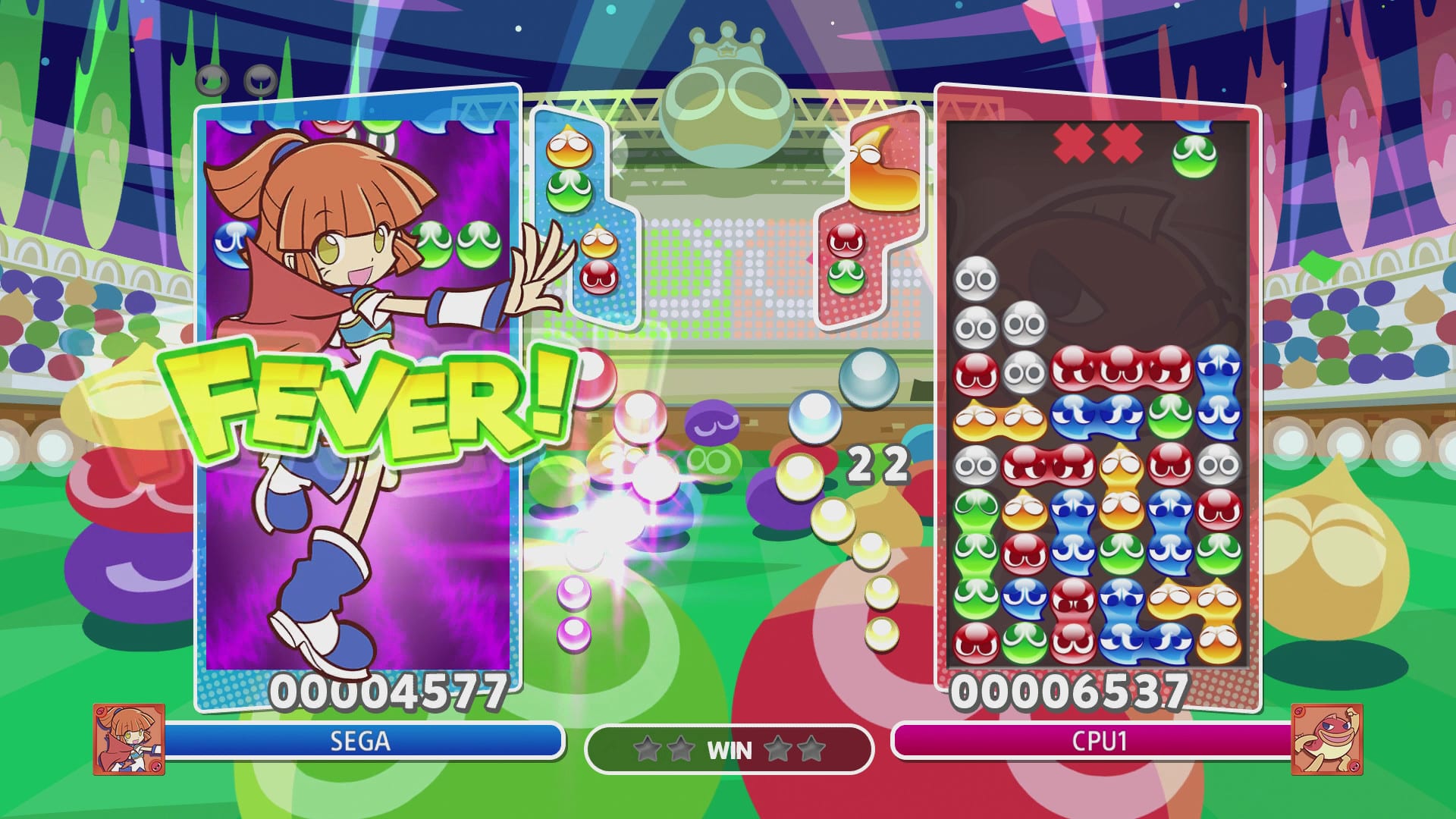 Un personaje animado celebra bajo el texto FEVER junto a columnas de blobs de colores apilados en una pantalla de videojuego dividida en dos paneles.