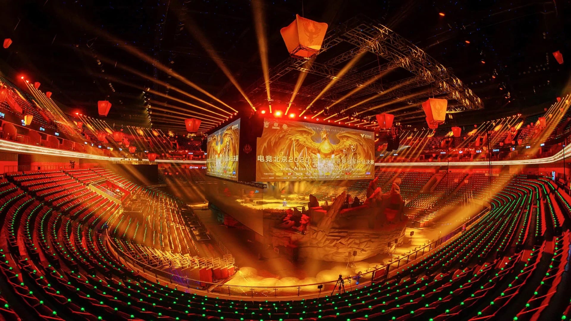 Vista de un estadio con gradas rojas, rayos de luz dorada y una pantalla central sobre un escenario, en la final mundial de Honor of Kings de 2020.