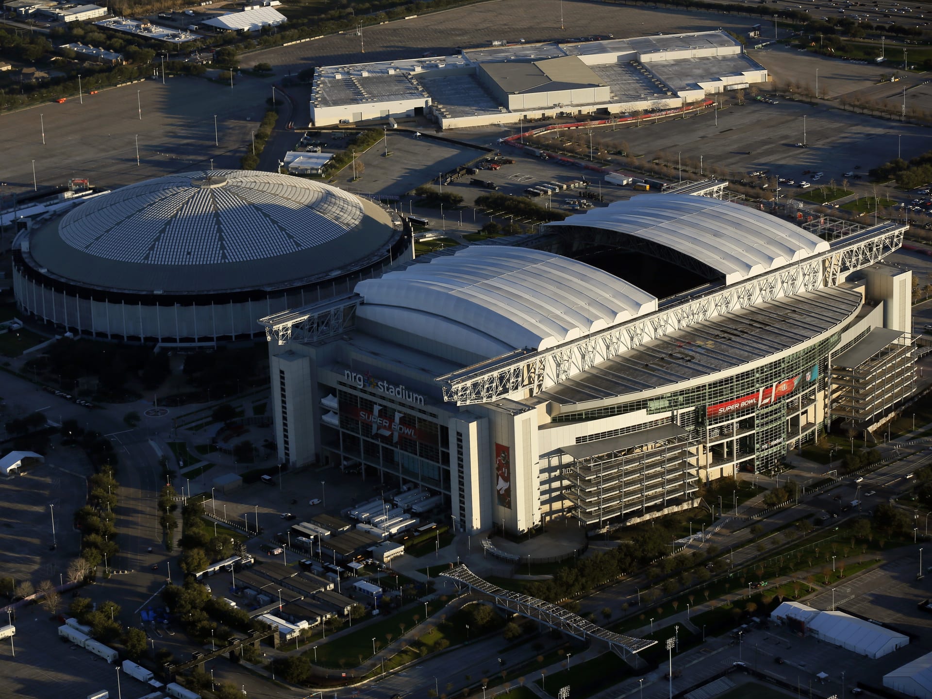 Vista aérea del NRG Stadium de Houston con su techo retráctil abierto y, a la izquierda, el Astrodome; las fachadas llevan rótulos del Super Bowl LI.