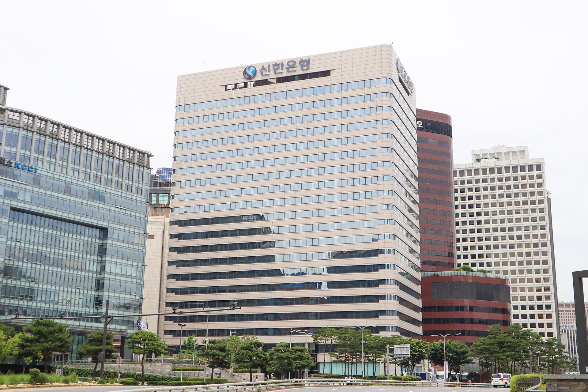 A multi-story office tower with the Shinhan Bank name and logo near the top, among other Seoul high-rises.