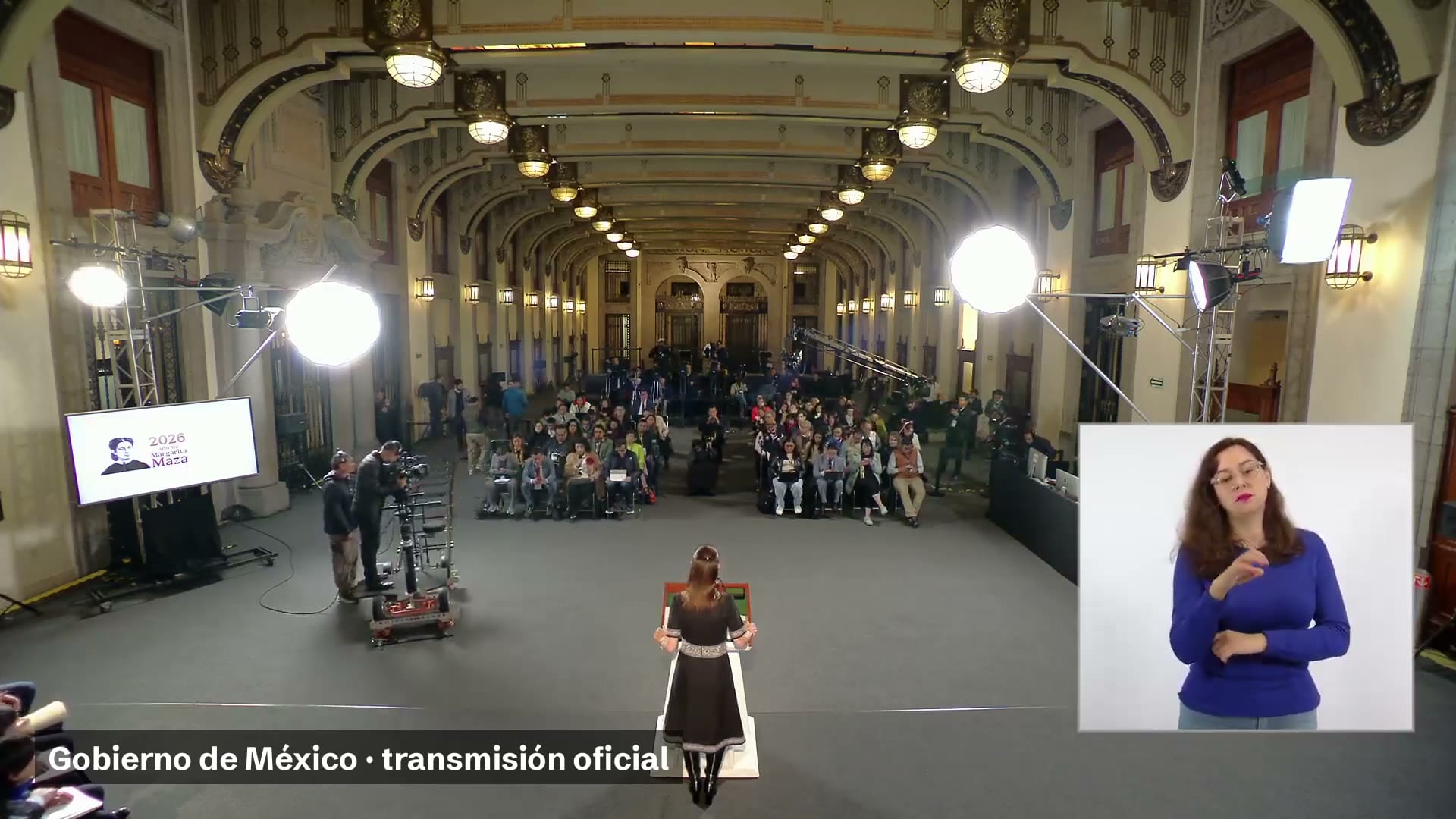 Vista general del salón de la conferencia matutina, con la presidenta de espaldas ante el podio, periodistas sentados y una intérprete de lengua de señas en un recuadro
