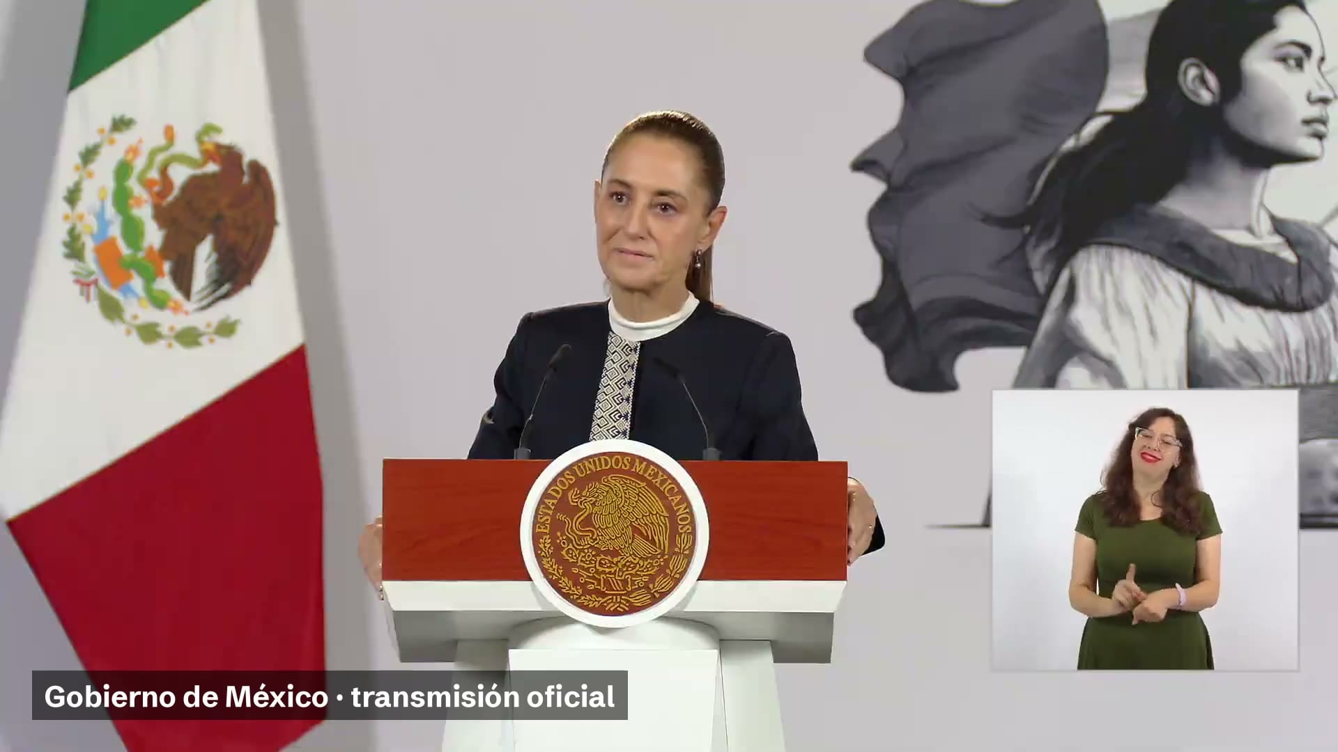 La presidenta Claudia Sheinbaum habla detrás del podio de la conferencia matutina, con la bandera de México a un lado y una intérprete de lengua de señas en un recuadro.