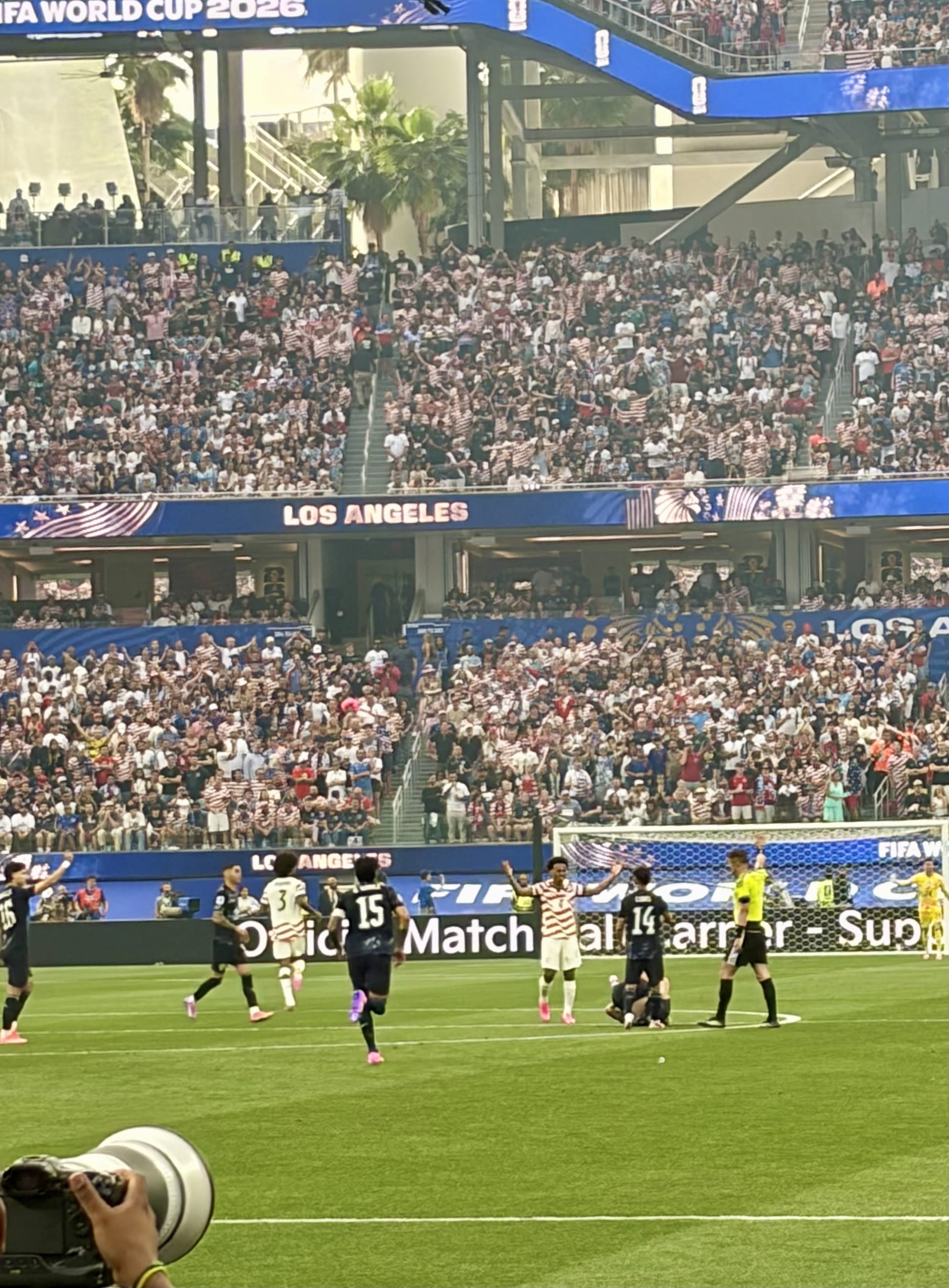 Jugadores celebran con los brazos en alto frente al arco, mientras un árbitro observa, en un estadio repleto con la marca del Mundial 2026 al fondo.