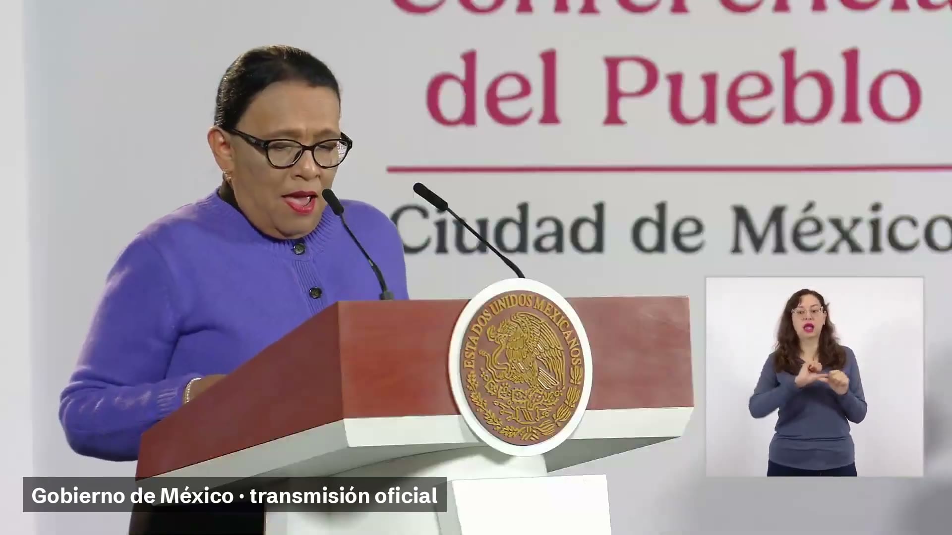 Una mujer de suéter morado habla desde un podio con el escudo nacional; a la derecha, una intérprete de lengua de señas.