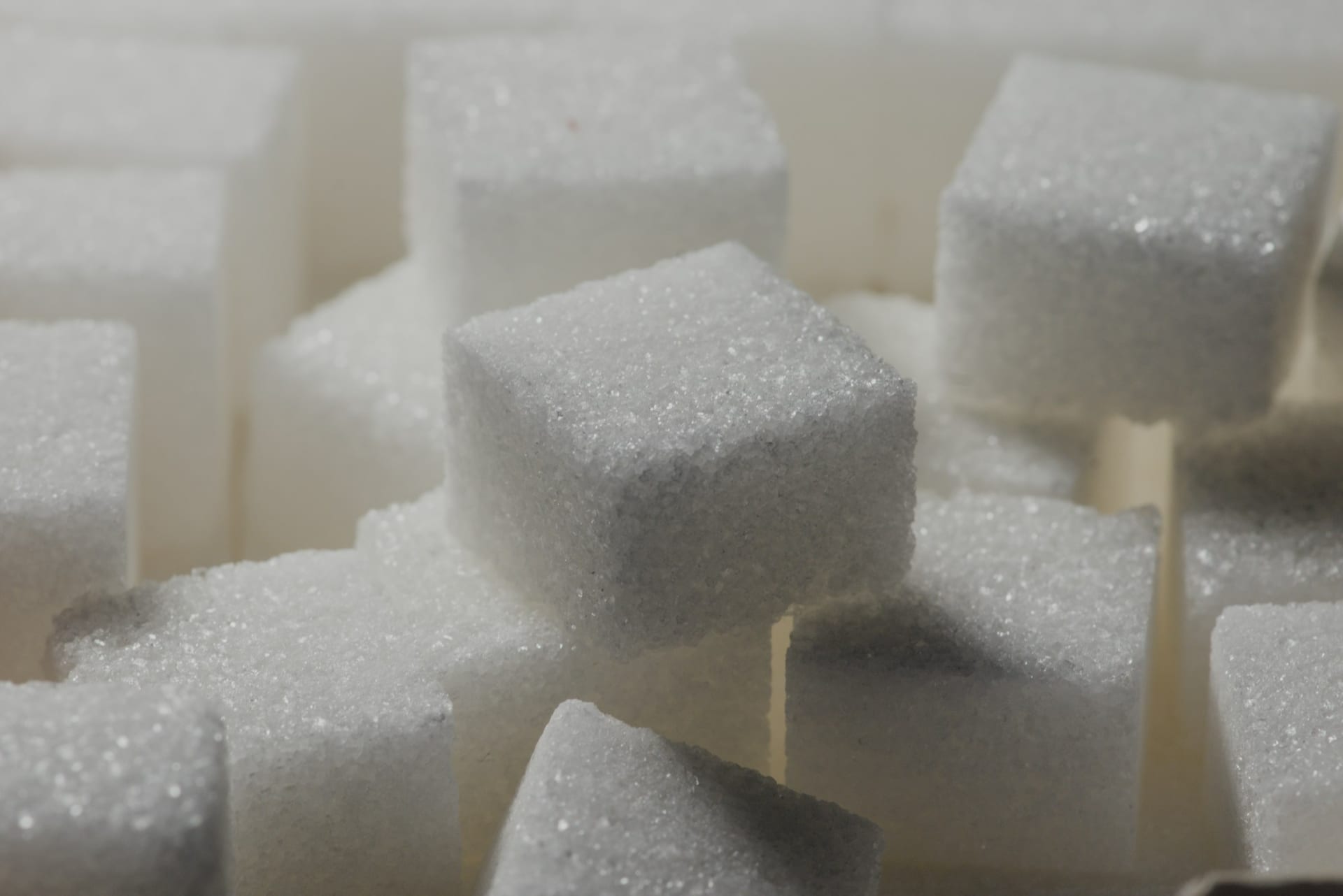 Un montón de terrones de azúcar blancos apilados unos sobre otros sobre una superficie clara.