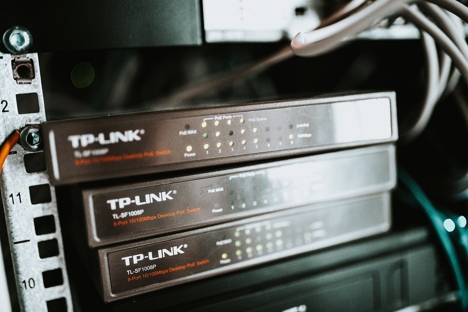 Tres switches de red TP-Link apilados en un rack, con luces LED encendidas en sus puertos.
