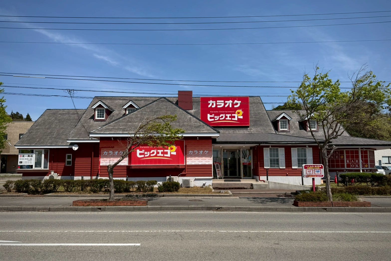 Fachada roja de un karaoke Big Echo con letreros en japonés, vista desde la calle bajo un cielo despejado.