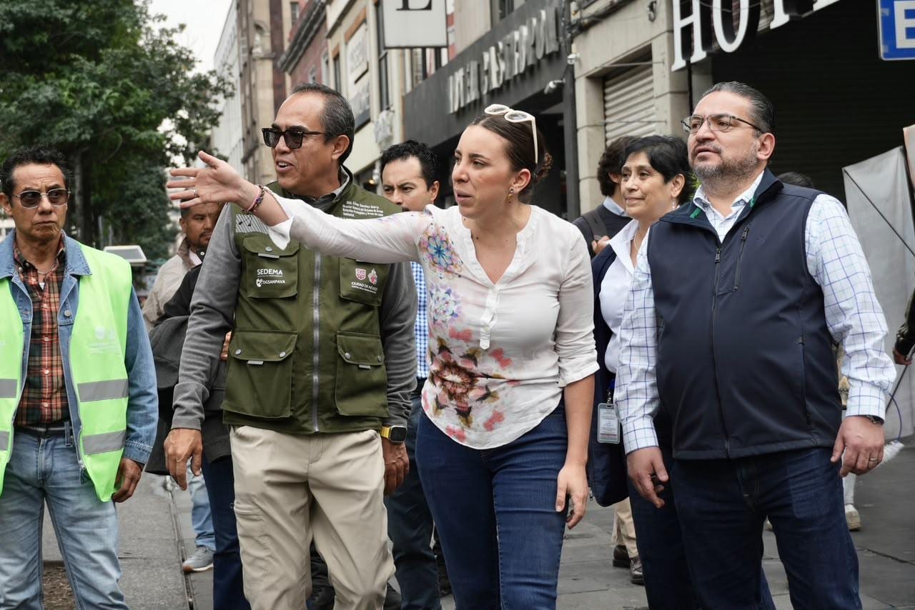Una mujer señala hacia adelante durante un recorrido por una calle del Centro Histórico, rodeada de funcionarios con chalecos de la Sedema.