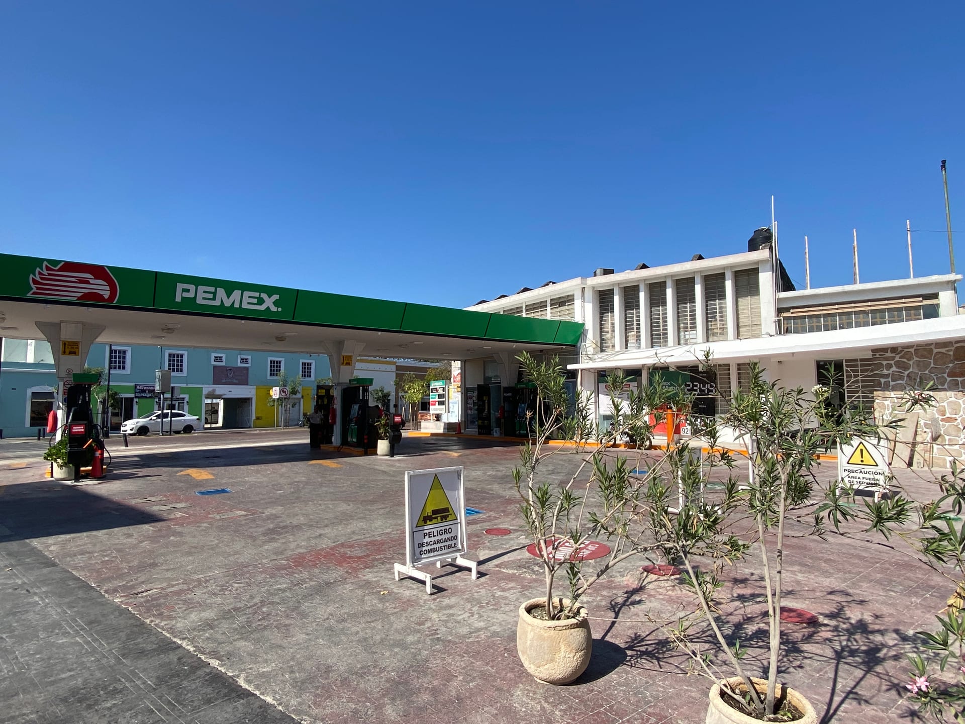 Una gasolinera con sus bombas bajo el techo de la estación, vista de frente.