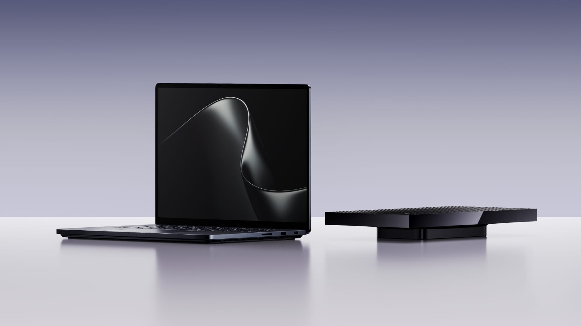 An open black laptop with a dark screen and silver waves, next to a flat black desktop unit on a light surface.