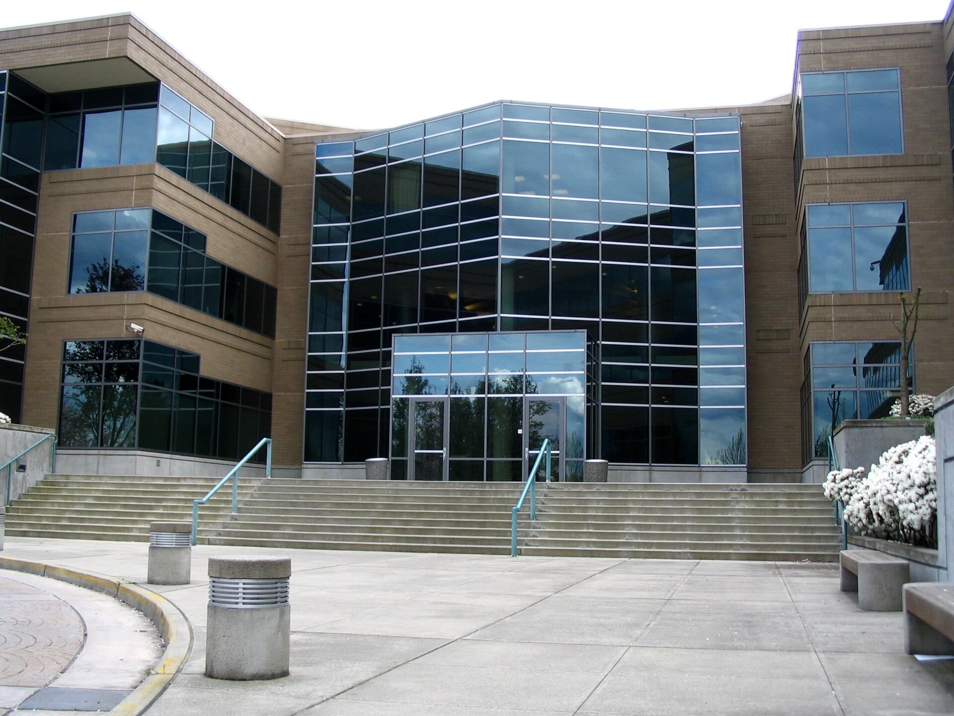 Glass and brick facade of an office building with a concrete staircase in front of the entrance.